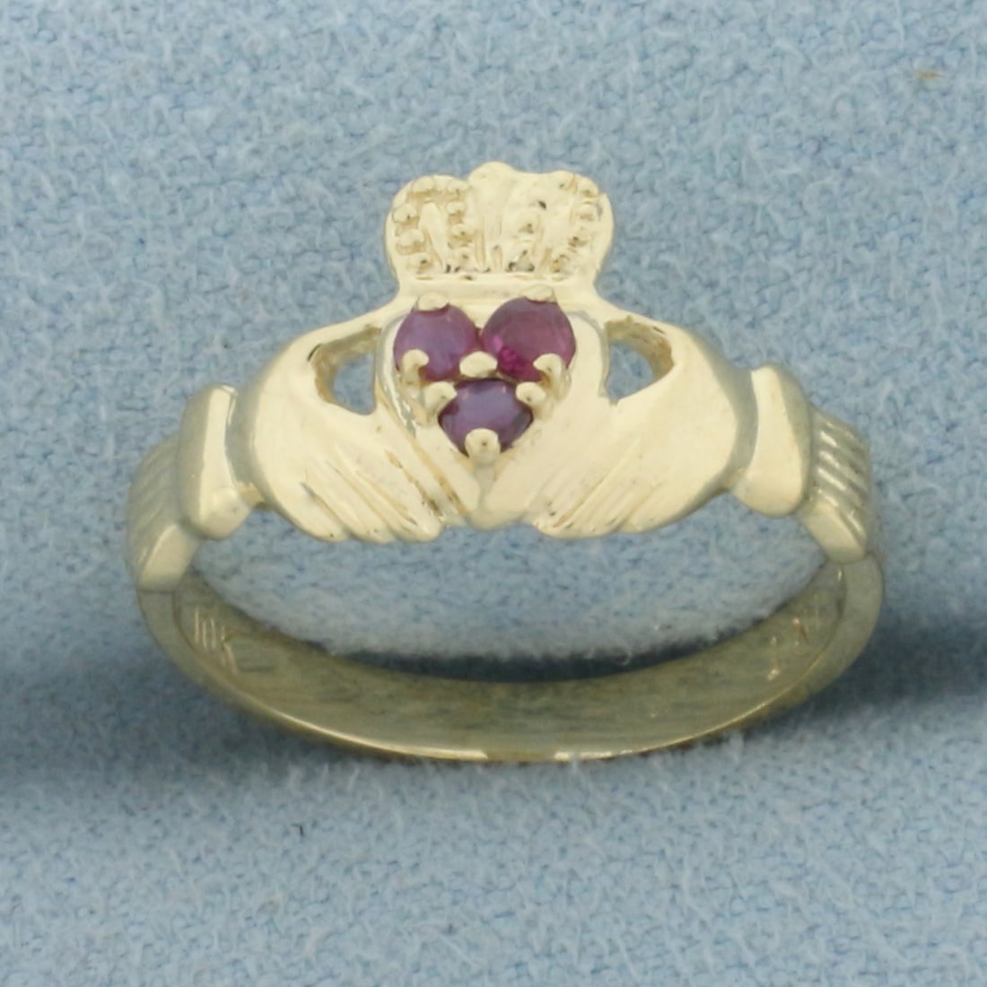 Ruby Claddagh Ring in 10k Yellow Gold: In 10k yellow gold. Contains three high quality natural 2mm Ruby gemstones with intense color and excellent clarity. 10mm wide at center of ring. Size: 5. 1.9g.