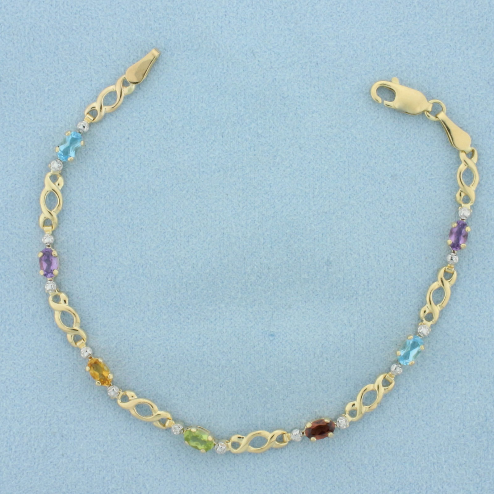 Rainbow Gemstone and Diamond Infinity Design Bracelet in 14k Yellow Gold: In 14k yellow gold. Contains 5mm high quality natural Blue Topaz, Amethyst, Citrine, peridot, and Garnet gemstones with bright color and excellent clarity. Also contains one 1/2pt diamond. Lobster cla