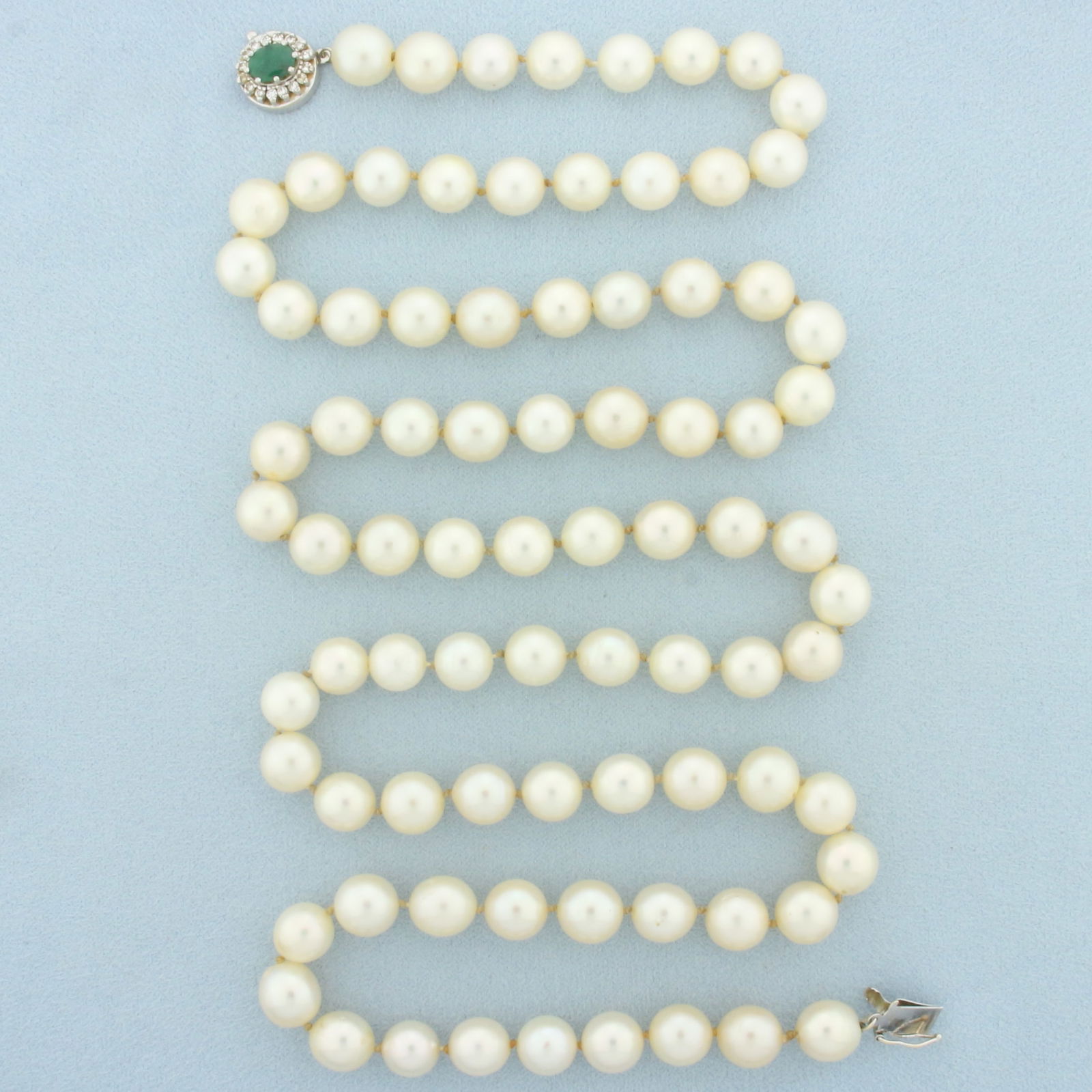 Vintage Emerald and Diamond 32 Inch Cultured Akoya Pearl Strand Necklace in 14k White Gold: Clasp in 14k white gold. Contains high quality 8mm cultured Akoya pearls with beautiful cream color and high luster. Clasp contains one high quality natural 6.5mm by 5mm Emerald gemstone with intense