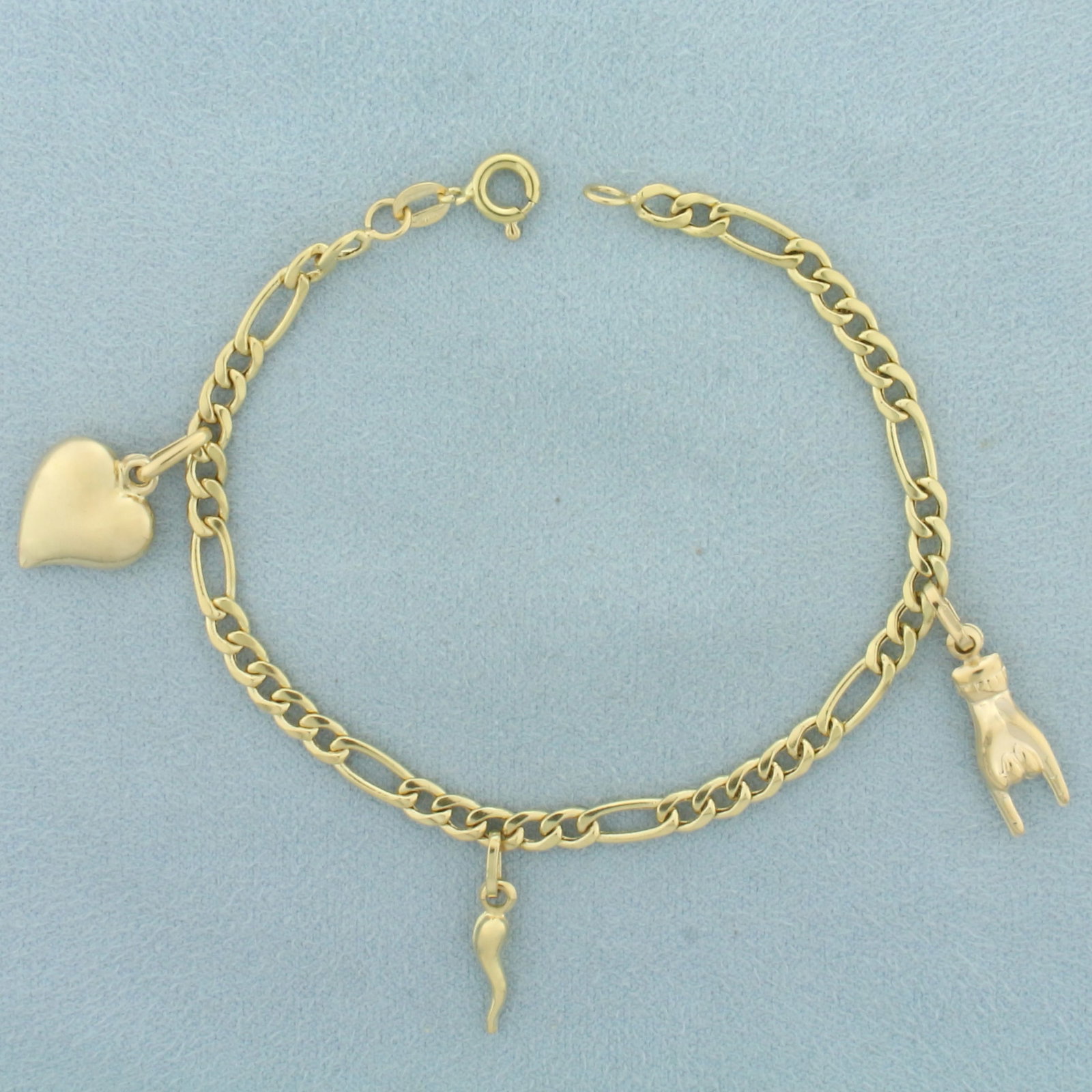 Figaro Link Charm Bracelet in 18k Yellow Gold: In 18k yellow gold. Contains 3 high quality gold charms: heart, Mano Cornuto Good Luck, and Italian Horn. 7 inches long and 3.70mm wide. Spring Ring Clasp. 6.6g.