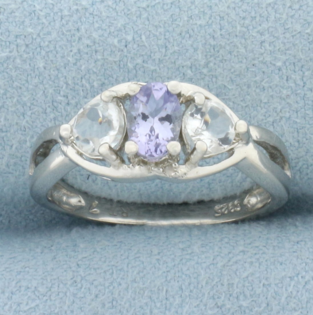 1CTW Tanzanite, White Topaz, and Diamond Ring in Platinum Over Sterling Silver: In platinum over sterling silver. Contains one oval cut tanzanite gemstone, .5 carat, accented with 2 white topaz gemstones, .5ctw, and two genuine diamonds, .01ctw. Size 7. 2.1g