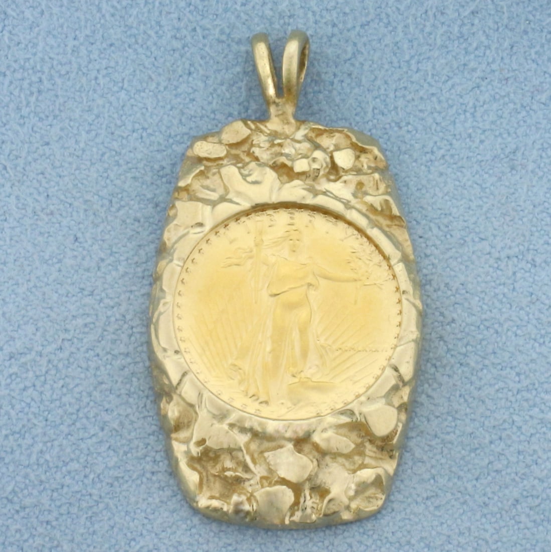 Gold Eagle Coin Pendant in 10k Yellow Gold: In 10k Yellow Gold Mounting. Contains one 1/10 ounce gold liberty coin from 1986. 1 3/8 inch long. 3/4 inch wide. 8.0g.