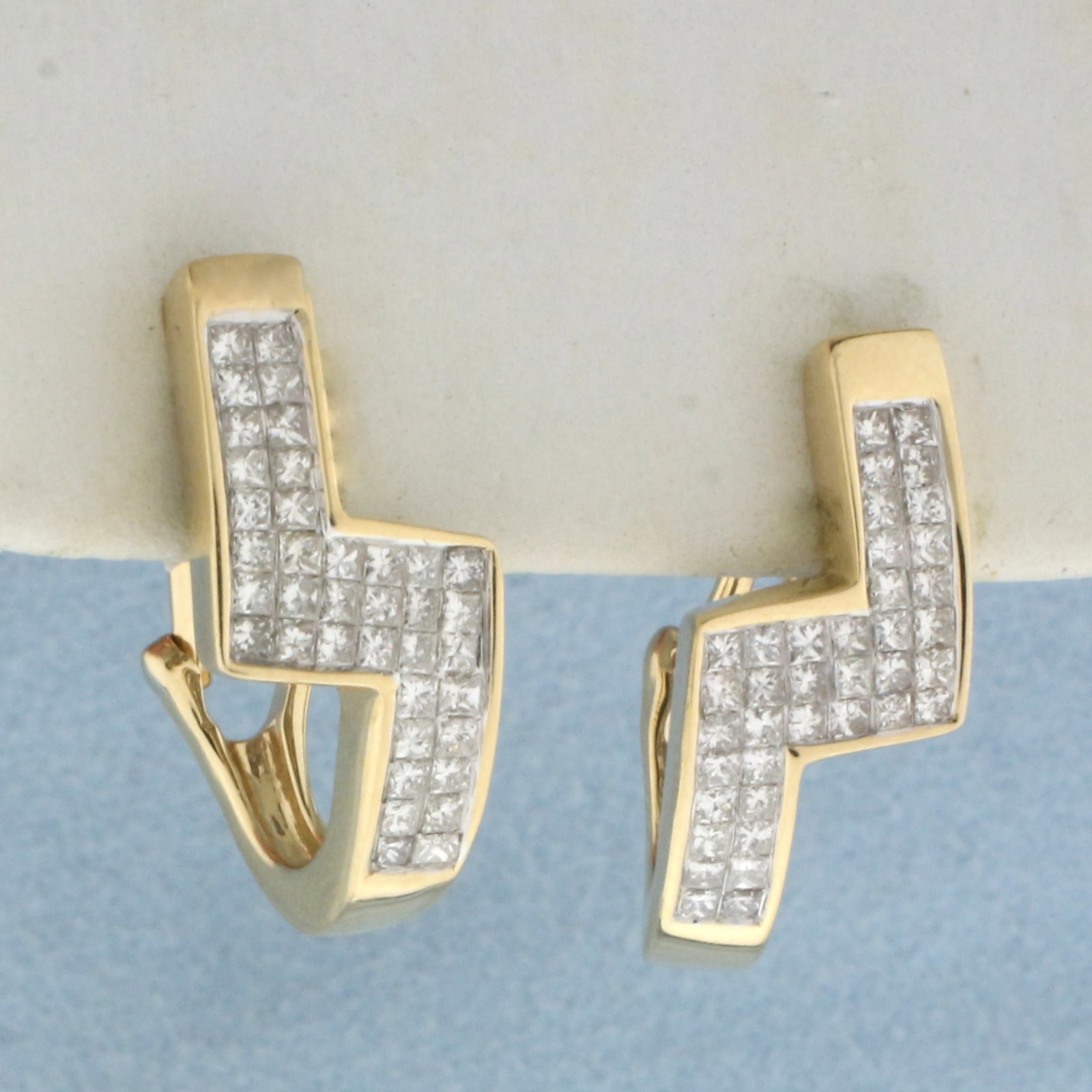 Invisible Set Diamond Zig Zag Design Earrings in 14k Yellow Gold: In 14k yellow gold. Contains seventy-six high quality princess cut diamonds, 1ct TW, SI1 clarity/H color. 3/4 inches long and 3/8 inches wide. Omega backs for added comfort. 5.9g.