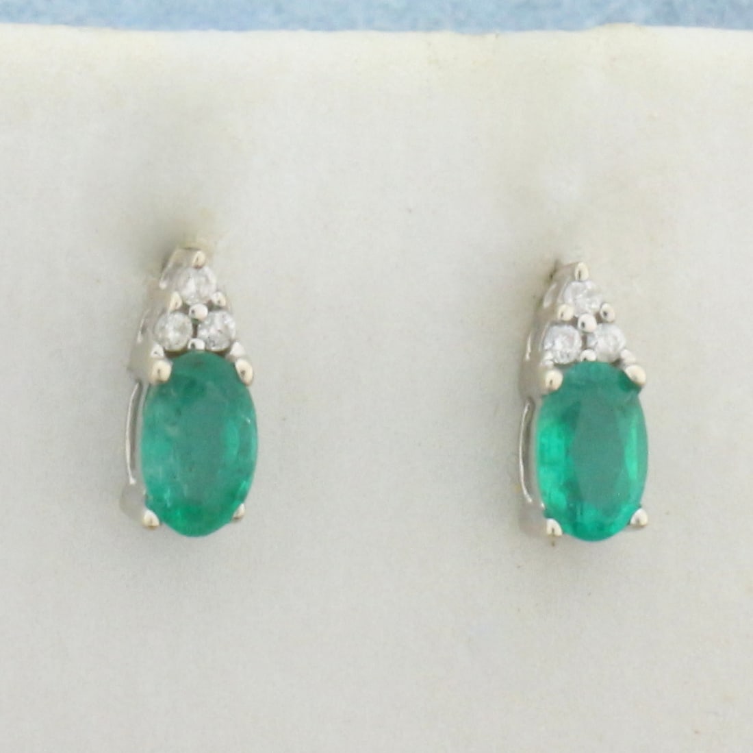 Emerald and Diamond Stud Earrings in 10k White Gold: In 10k White Gold. Contains two high quality natural 1/4ct Emerald gemstones with intense color. Also contains six .01ct diamonds, SI clarity/H color. 1/4 inch long. 1/8 inch wide. Friction backs. .8g