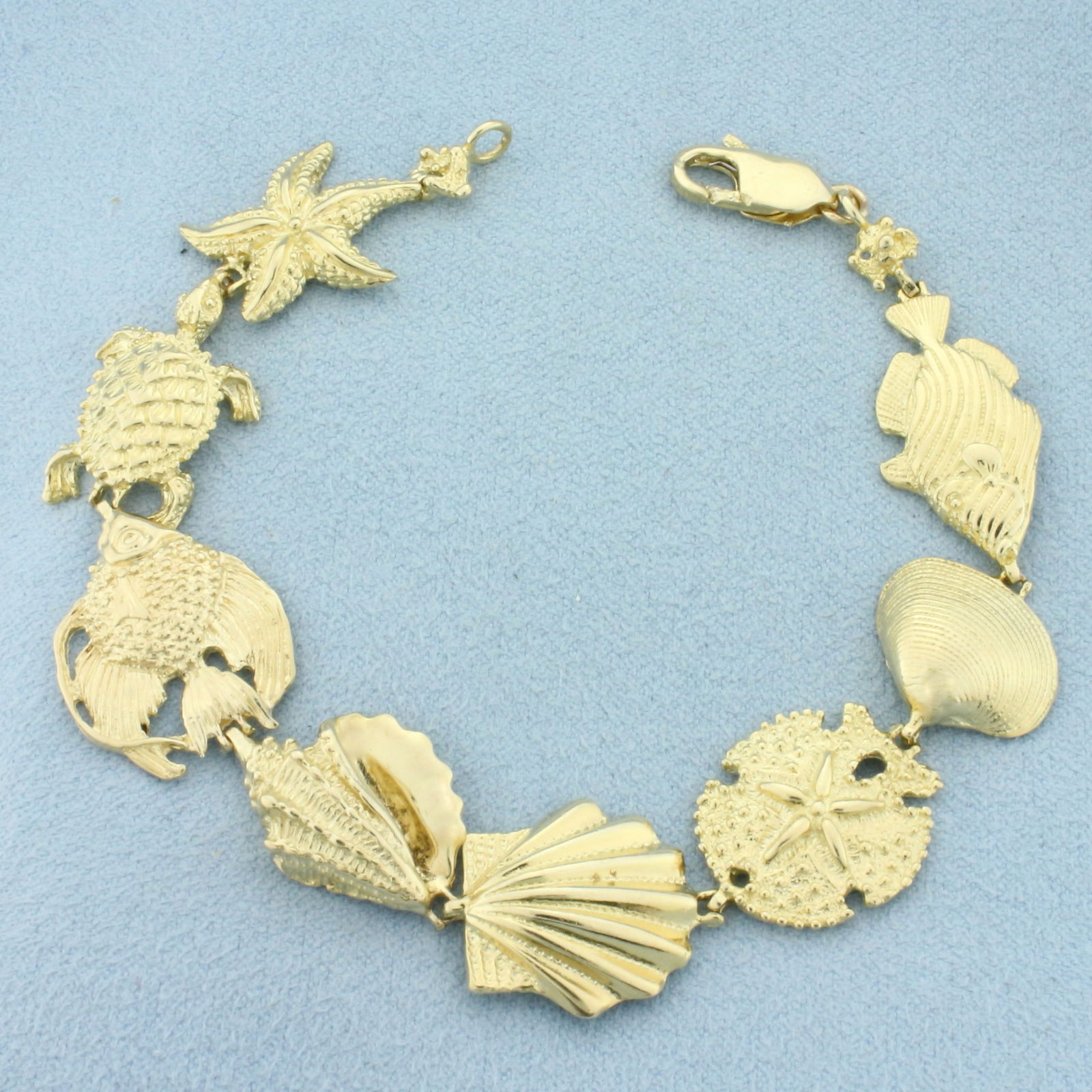 Sea Life Fish Shell Turtle Sand Dollar Starfish Bracelet in 14k Yellow Gold: In 14k Yellow Gold. 7 1/4 inch long. 5/8 inch wide. Lobster clasp. 17.5g.