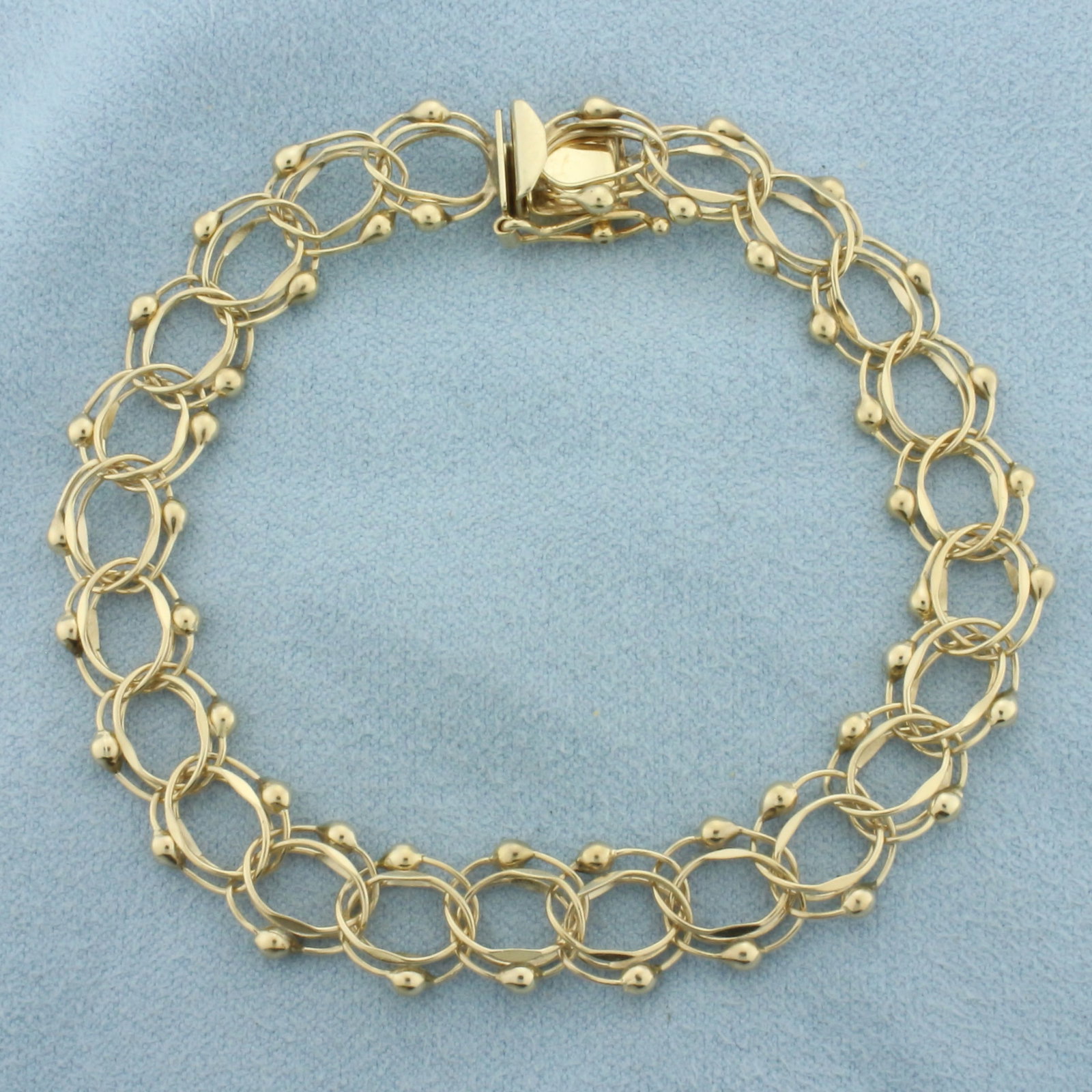 Double Loop Charm Bracelet in 14k Yellow Gold: In 14k Yellow Gold. 8 inch long. 3/8 inch wide. Concealed slide clasp with safety latch. 10.5g.