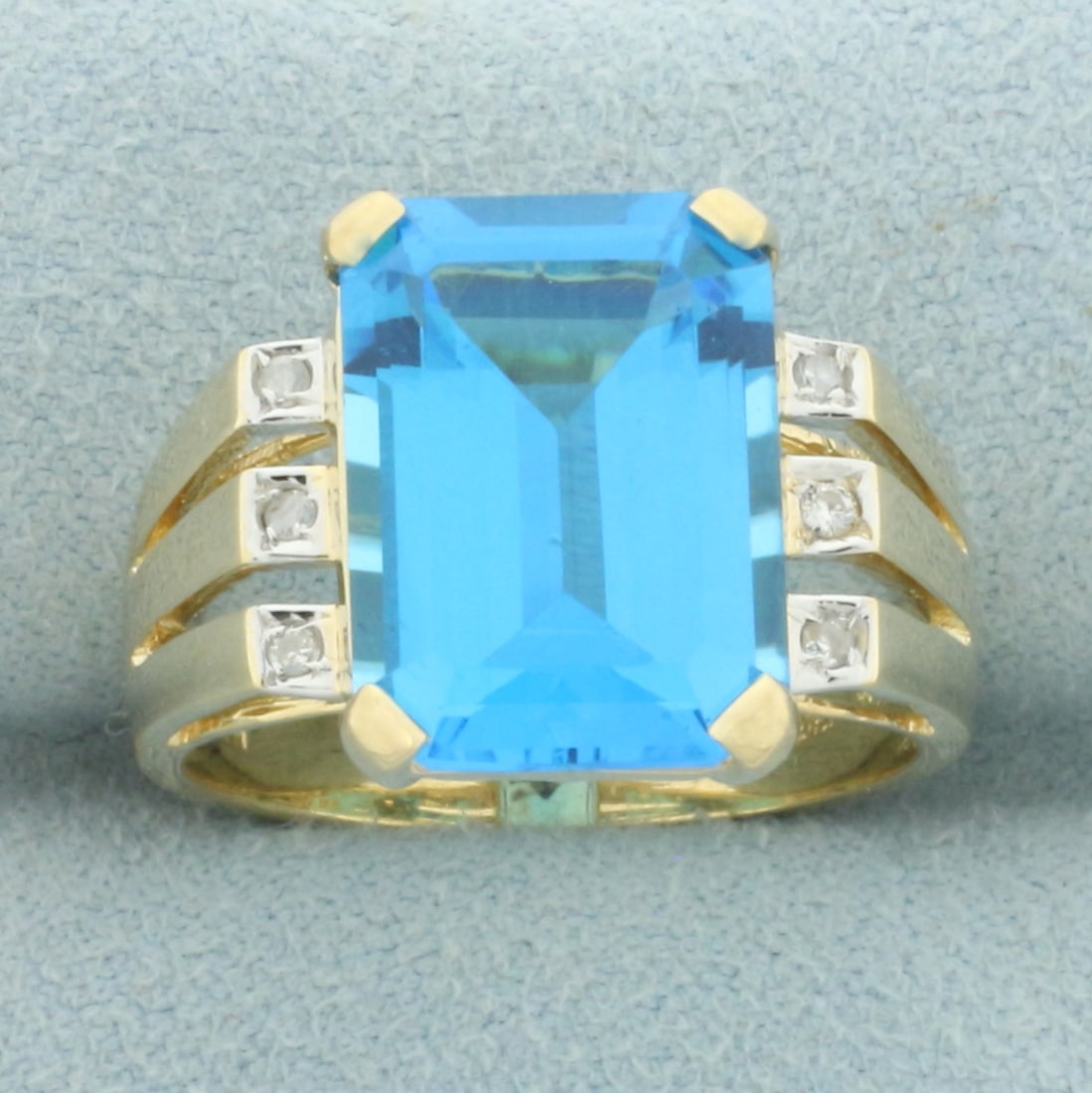 Swiss Blue Topaz and Diamond Statement Ring in 14k Yellow Gold: In 14k yellow gold. Contains one high quality 14mm by 10mm emerald cut Swiss Blue Topaz gemstone, approximately 8cts, with electric blue color and excellent clarity. Also contains six high quality .01
