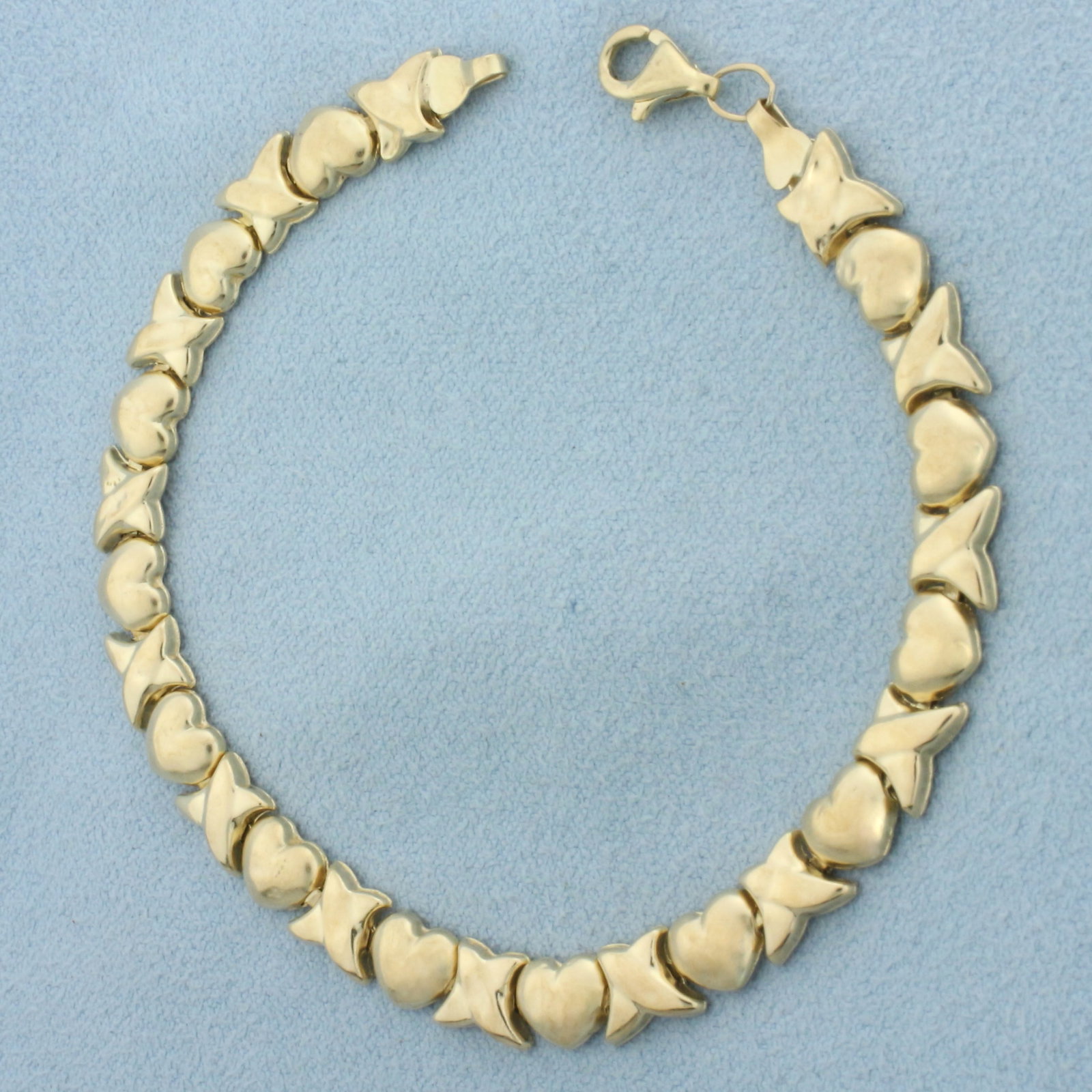Puffy X's and O's Bracelet in 10k Yellow Gold: In 10k yellow gold. 7 1/4 inches long and 1/4 inch wide. Small dents, not noticeable. Lobster clasp. 4.1g.