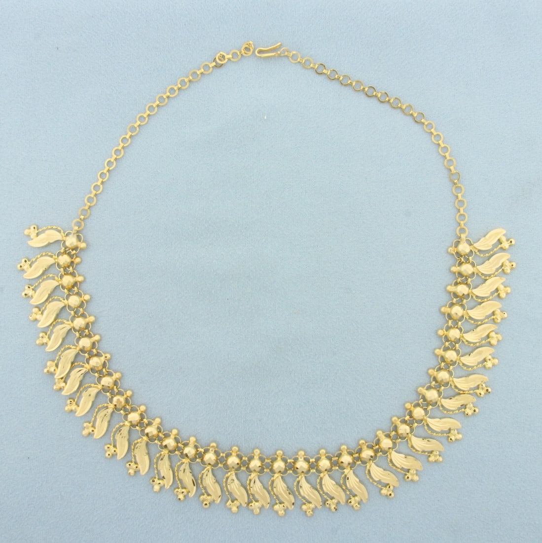 Diamond Cut Leaf Design Necklace in 22k Yellow Gold: In 22k yellow gold. 15 inches long. 3/4 inch wide at base off necklace. Diamond cut for added reflection. Hook clasp. 20.6g.