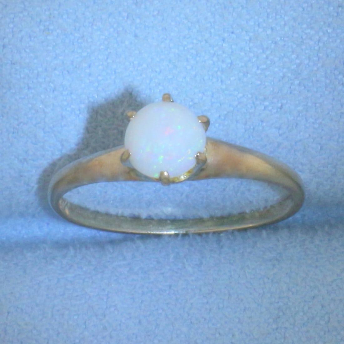 Opal Solitaire Ring in 10k Yellow Gold: In 10k Yellow Gold. Contains one high quality natural 5.4mm opal gemstone with excellent play of color and flashes of red, orange, blue, and green. 6-prong design. Size 6.5. 1.4g.