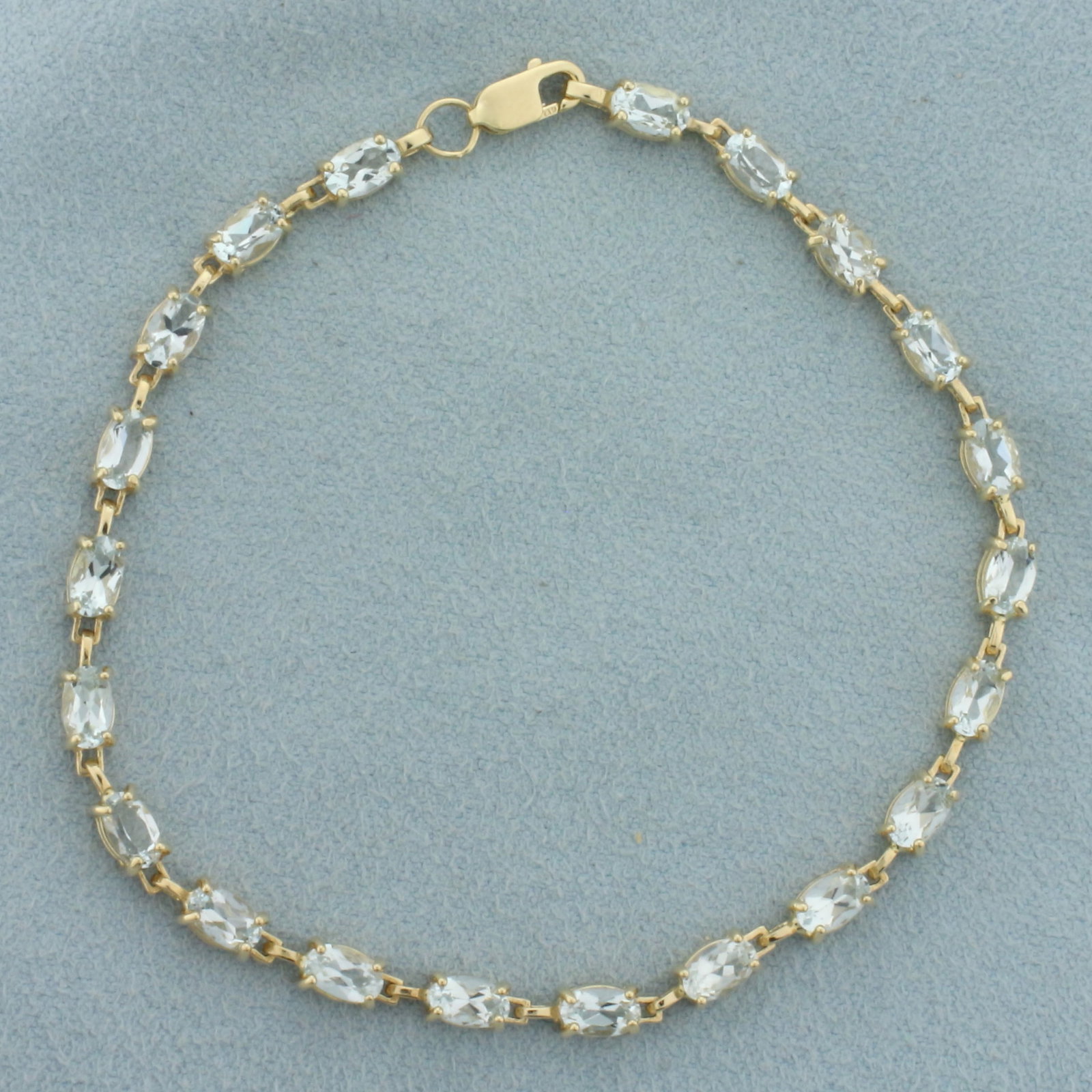 Aquamarine Tennis Bracelet in 10k Yellow Gold: In 10k yellow gold. Contains twenty-one high quality natural 5mm oval aquamarine gemstones with excellent clarity. 5ct TW. Lobster clasp. 7 inches long and 3.4mm wide. 4.7g.