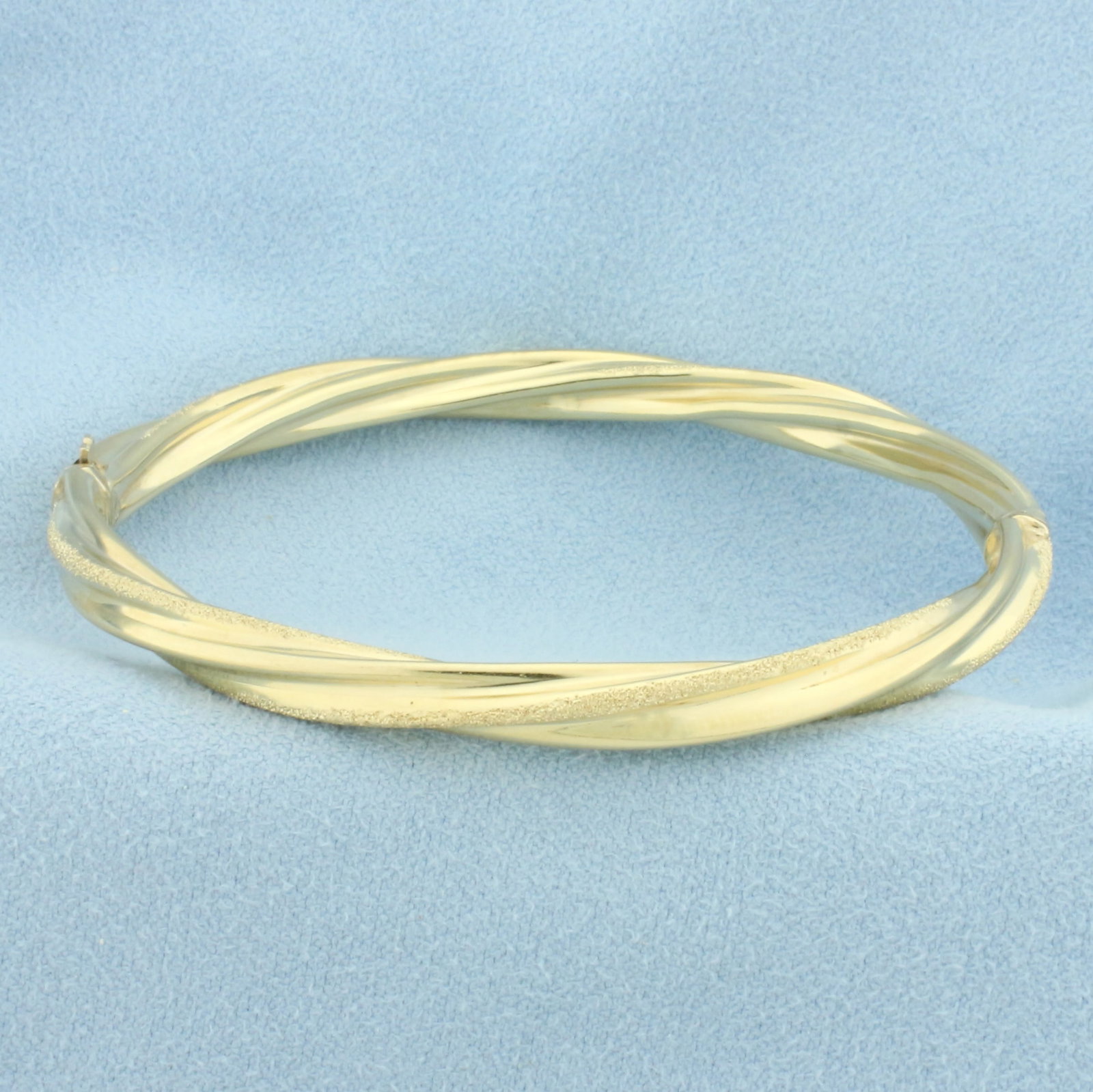 Twisting Rope Design Bangle Bracelet in 14k Yellow Gold: In 14k yellow gold. Interior dimensions: 2 3/8 inches by 2 1/8 inches. 5.1mm wide. High polish and sparkle finishes. Hinged slide closure for easy putting on/taking off. 9.1g.