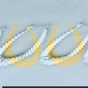 Large Oval Twisting Design Hoop Earrings in 14k Yellow Gold: In 14k Yellow Gold. 1 3/8 inch long. 1 1/8 inch wide. Leverbacks. 3.2g.