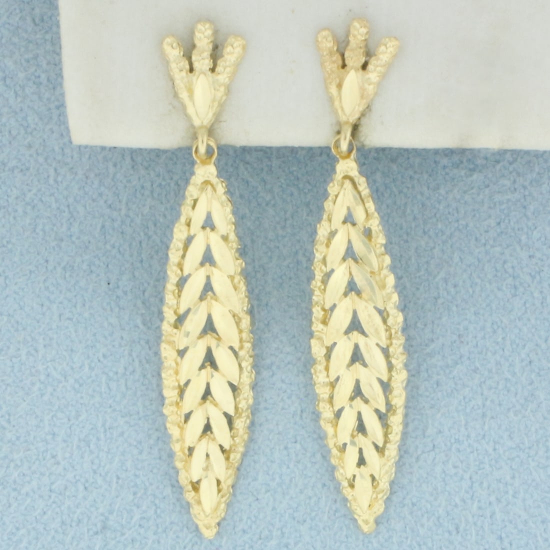 Diamond Cut Leaf Nature Design Dangle Earrings in 14k Yellow Gold: In 14k Yellow Gold. 1 1/2 inch long. 1/4 inch wide. Friction backs. 2.7g.