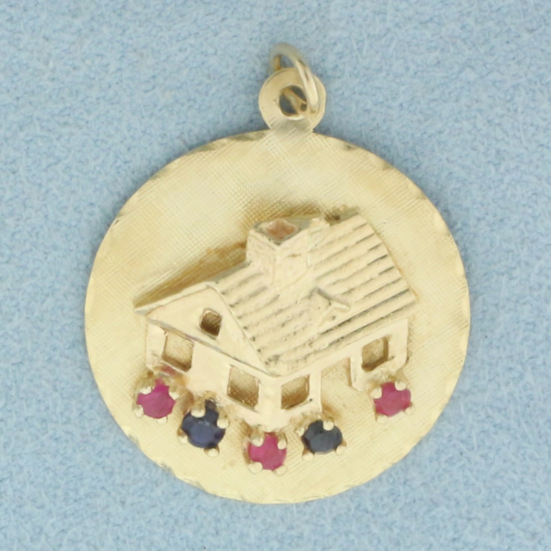 Engravable Ruby and Sapphire House Charm in 14k Yellow Gold: In 14k Yellow Gold. Contains three Ruby and three Sapphire 2mm high quality natural gemstones. 1 1/8 inch long including jump ring. 7/8 inch wide. Blank back to engrave name or date. 4.3g.