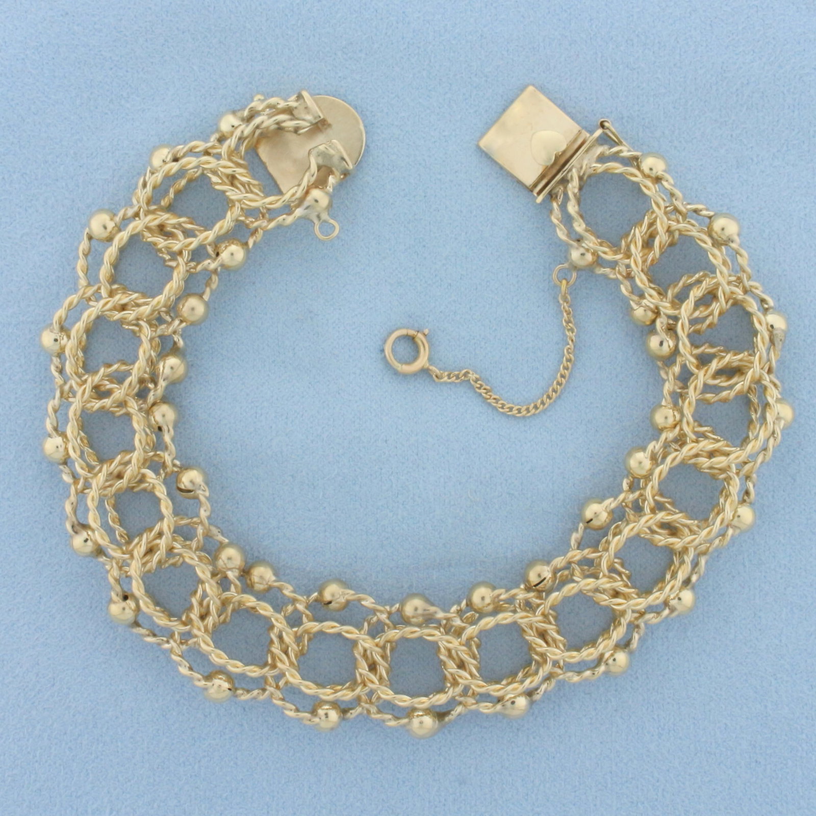 Wide Twisting Loop Rope Charm Bracelet in 14k Yellow Gold: In 14k yellow gold. 7 1/2 inches long and 5/8 inches wide. Slide heart clasp with safety chain and safety latch. 40.7g.