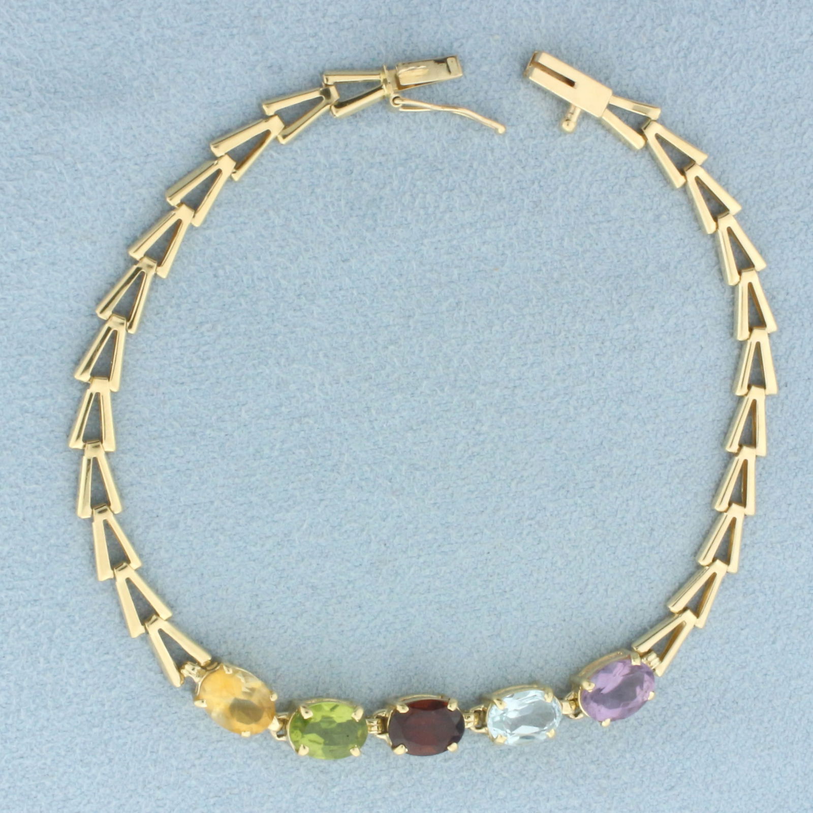 Rainbow Gemstone Bracelet in 14k Yellow Gold: In 14k Yellow Gold. Contains 5x7mm high quality oval cut natural gemstones: Amethyst, Blue Topaz, Garnet, Peridot, and Citrine, all with bright color and excellent clarity. 7 1/8 inches long. 5mm wide