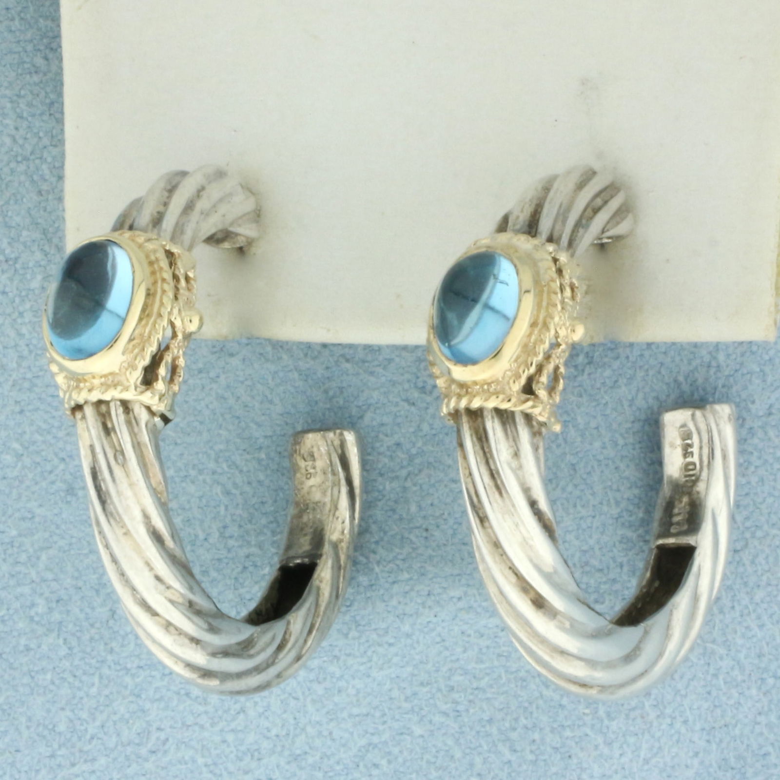 Blue Topaz Hoop Earrings in 14k Yellow Gold and Sterling Silver: In .925 Sterling Silver and 14k Yellow Gold. Contains two 5x7mm high quality natural Blue Topaz gemstones with bright color and excellent clarity. 1 1/8 inch long. 1 1/8 inch wide. Friction backs. 9.9