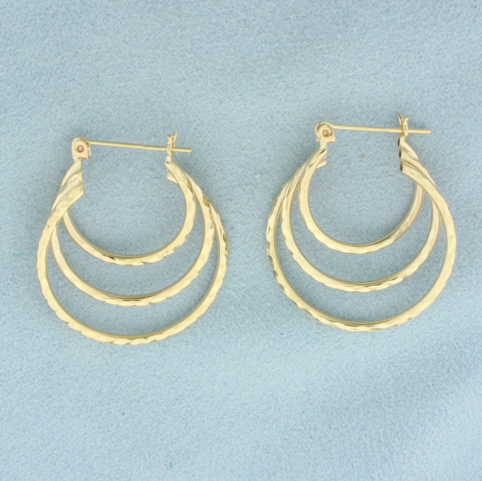 Diamond Cut Triple Hoop Earrings in 14k Yellow Gold: In 14k Yellow Gold. 1 1/8 inch long. 1 inch wide. Leverbacks. 2.8g.