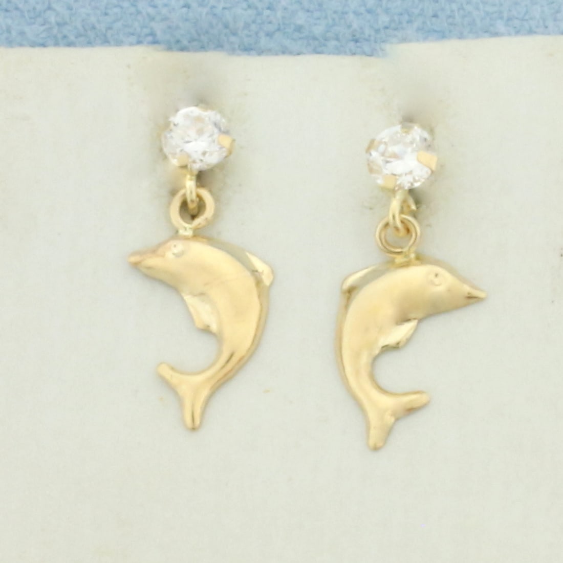 Dolphin Dangle Earrings in 14k Yellow Gold: In 14k Yellow Gold. Contains two 3mm high quality CZ gemstones. 1/2 inch long. 1/4 inch wide. Friction backs. .5g.