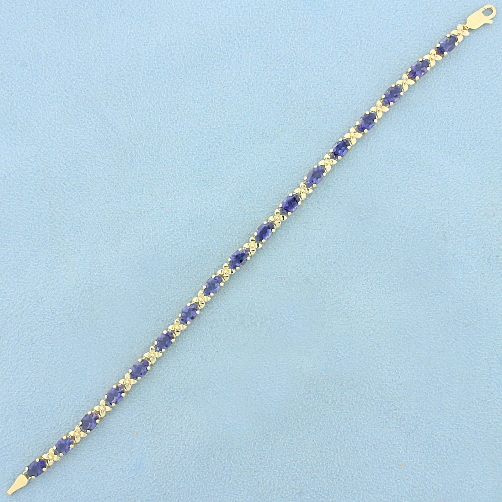 AAA Tanzanite Flower Design Line Bracelet in 14K Yellow Gold: In 14K Yellow Gold. Contains seventeen very high AAA quality natural 6mmx4mm oval Tanzanite gemstones with intense sapphire like blue color and excellent clarity. 8.5ct TW. 7 1/4 inches long. 4.4mm wi