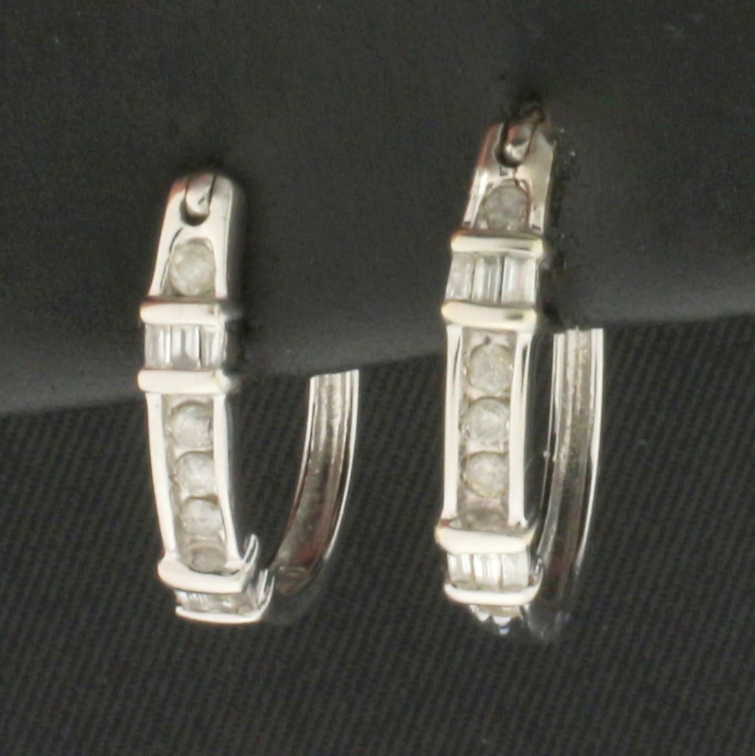 Diamond Hoop Earrings in 10k White Gold: In 10k White Gold. Contains ten high quality .01ct round diamonds. Also contains twelve high quality.01ct baguette diamonds. 5/8 inch long. 5/8 inch wide profile. 2.0g.