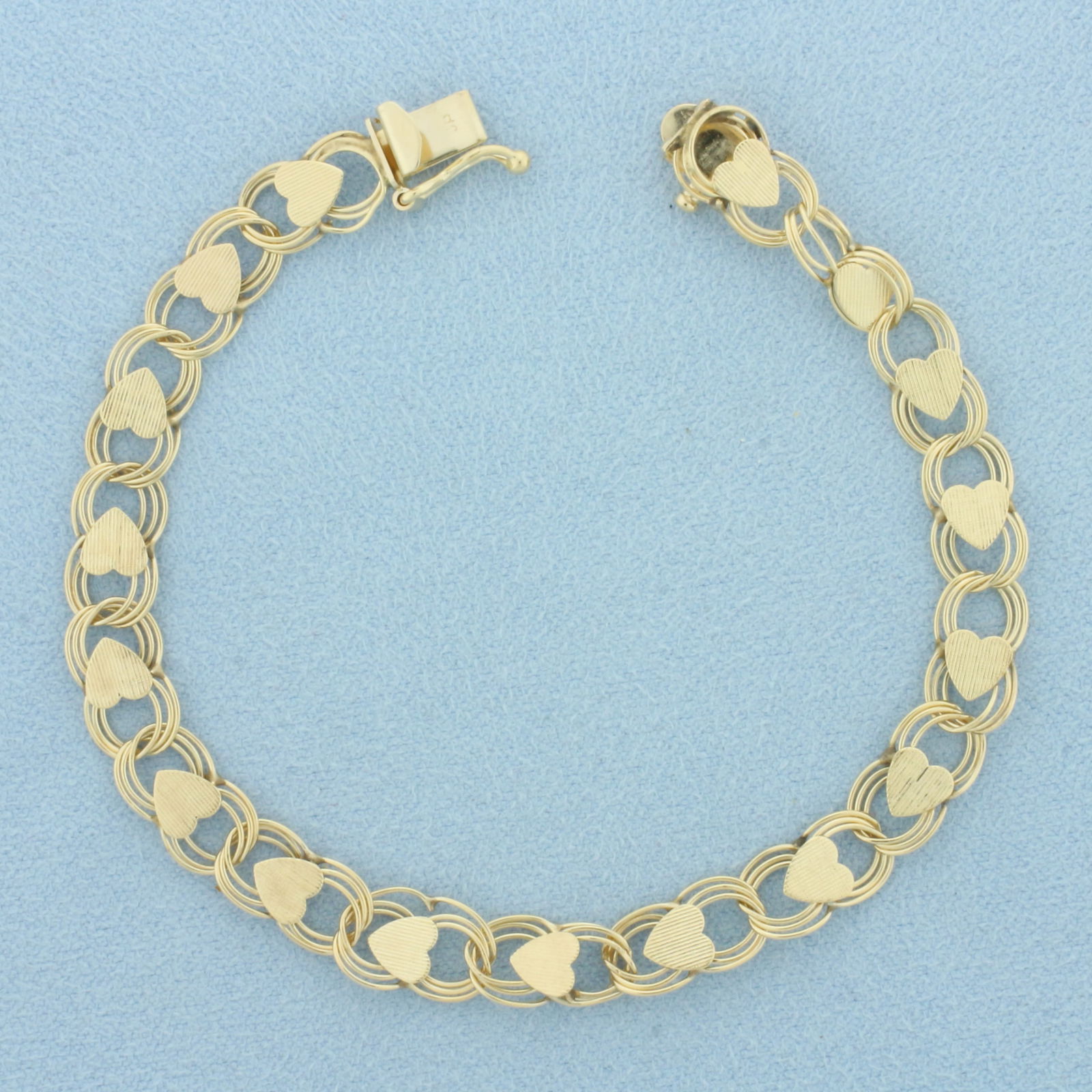 Heart Link Charm Bracelet in 14k Yellow Gold: In 14k Yellow Gold. 7 inches long. 7mm wide. Concealed slide clasp with safety latch. 6.1g.