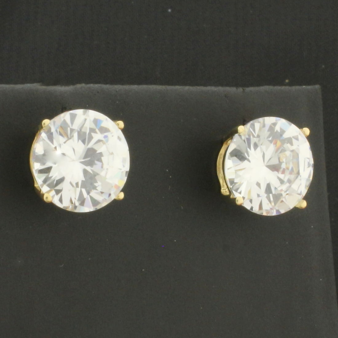 7ct CZ Stud Earrings in 14k Yellow Gold: In 14k Yellow Gold. Contains two 10mm high quality CZ gemstones with excellent cut and clarity for added brilliance. 7ct Total Weight. 4 prong basket setting. Friction backs. 3.4g.