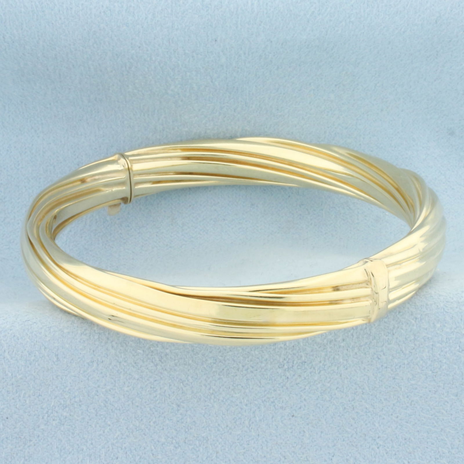 Hinged Twisting Design Bangle Bracelet in 14k Yellow Gold: In 14k Yellow Gold. Interior dimensions: 2 3/8 inch by 2 1/8 inch. 8.2mm wide. Hinged slide bar closure. 16.8g.