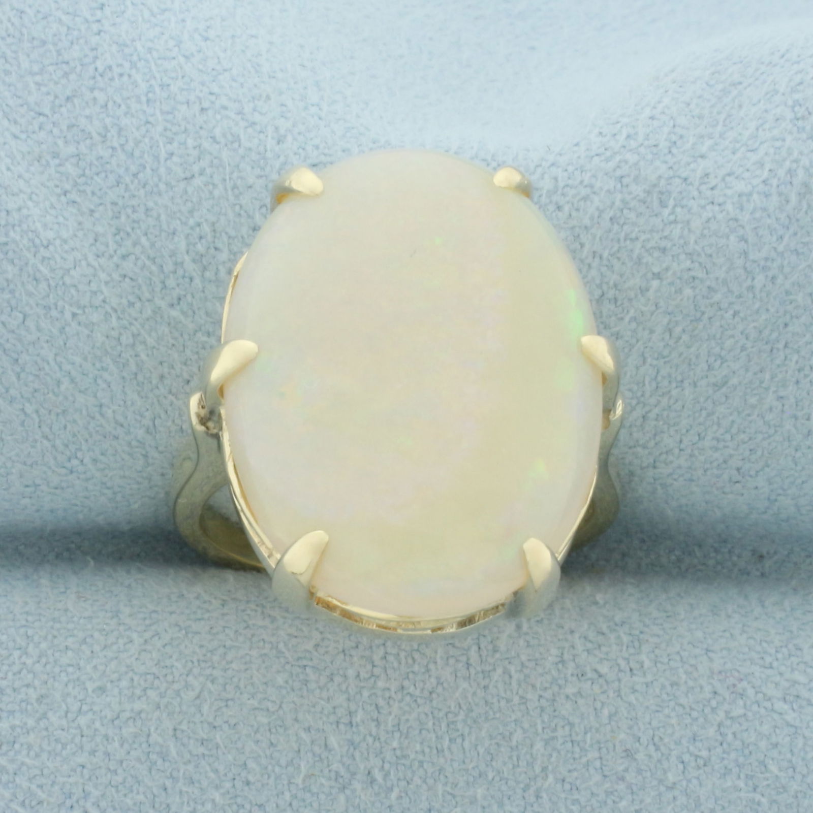 12ct Opal Solitaire Statement Ring in 14k Yellow Gold: In 14k yellow gold. Contains one high quality natural opal, 22.5mm by 16.3mm, 12 cts, with excellent play of color featuring flashes of orange, purple, pink, green, yellow. Size: 8. 7.7g.
