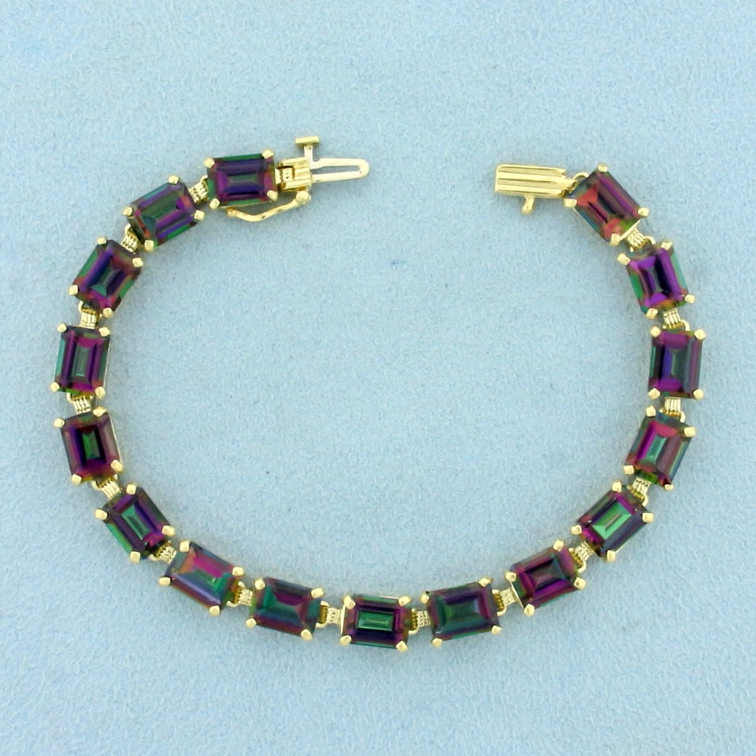 Mystic Topaz Line Tennis Bracelet in 14K Yellow Gold: In 14K Yellow Gold. Contains sixteen high quality natural 8x6mm mystic topaz gemstones, 24ct TW, with vibrant color and excellent clarity. 7 inches long, 6.9mm wide. Safety clasp. 16.2g.