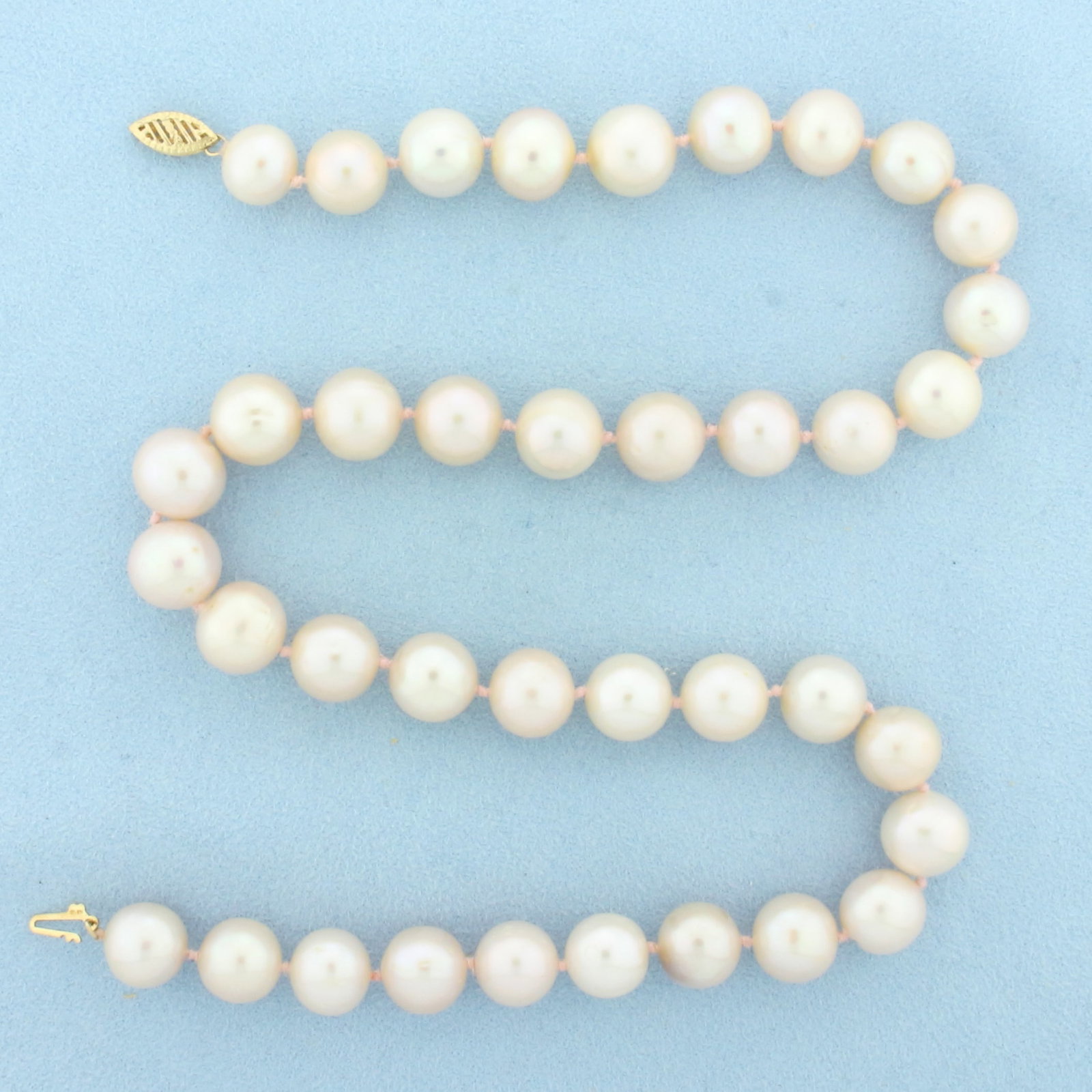 Pink Cultured Akoya Pearl Strand Necklace in 14k Yellow Gold: 14k Yellow Gold clasp. 18 1/4 inches long. Contains 11mm high quality Akoya Pearls with high luster and beautiful pink undertone. Hand knotted on pink thread. Decorative filigree clasp. 67.0g.