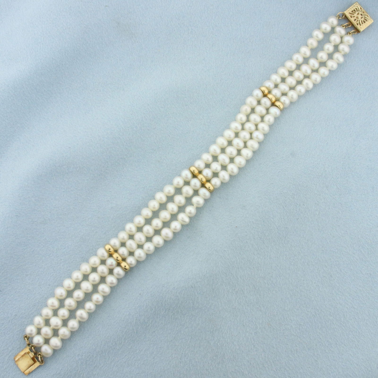 Triple Strand Cultured Pearl Bracelet in 14k Yellow Gold: 14k yellow gold clasp and spacers. Hand knotted. High quality cultured pearls range from 4.5-4.8mm each with high luster. Decorative Filigree clasp. 14.8g.