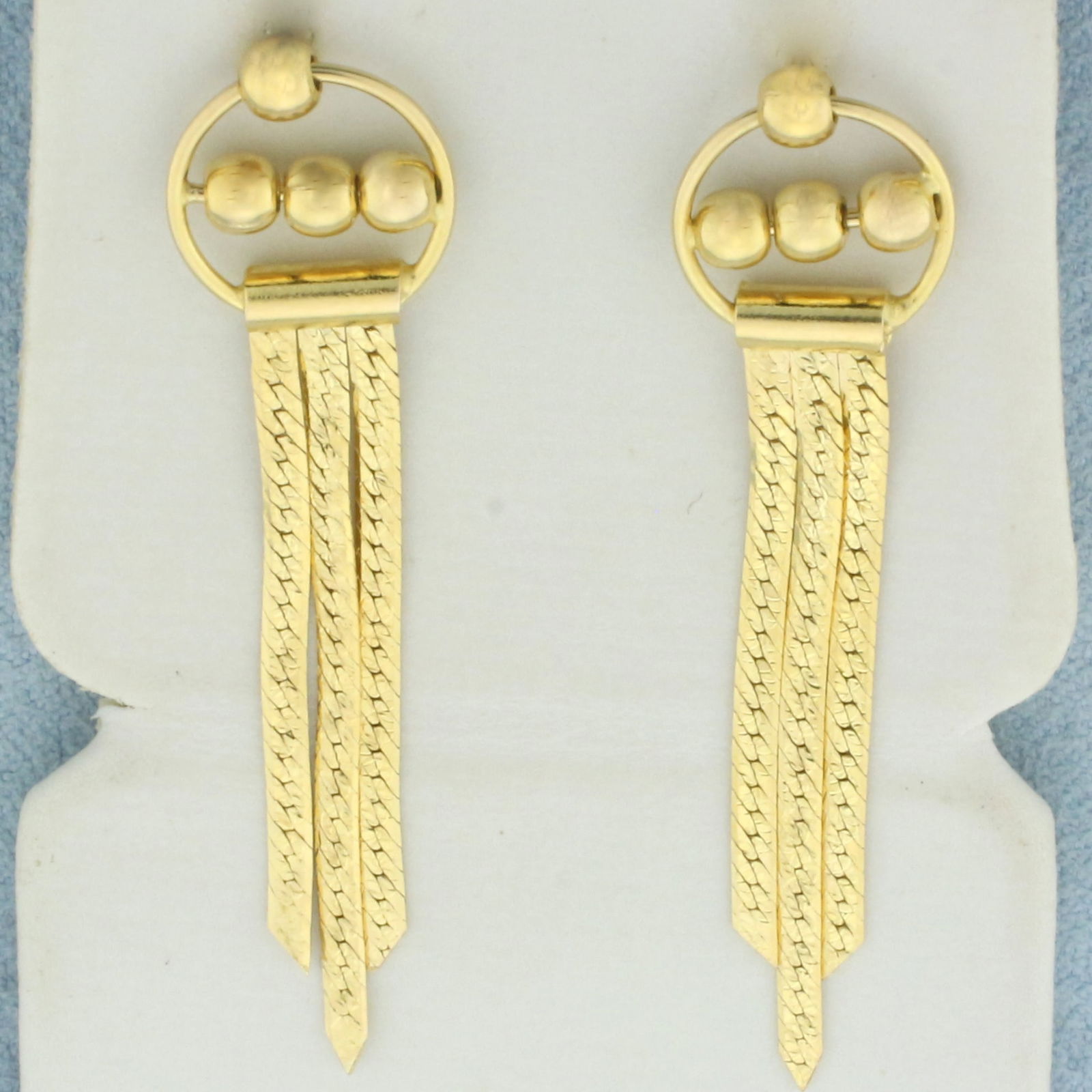 Reversable Herringbone Ball Bead Dangle Earrings in 14k Yellow Gold: In 14k Yellow Gold. 1 3/4 inch long. 3/8 inch wide. Reversable - traditional herringbone design on one side, diamond cut design on other side, like two earrings in one. Bull beads spin in center. Fric