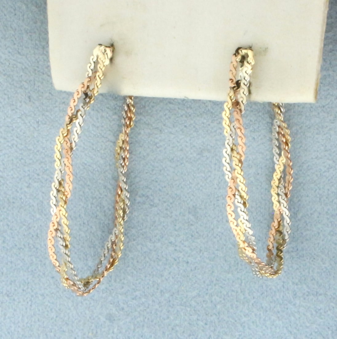Tri-Color Braided S-Link Front to Back Hoop Earrings in 14k Yellow, Rose, and White Gold: In 14k Yellow, Rose, and White Gold. 1 3/8 inch long. 3.6mm wide. Front to back design. Friction backs. 2.6g.
