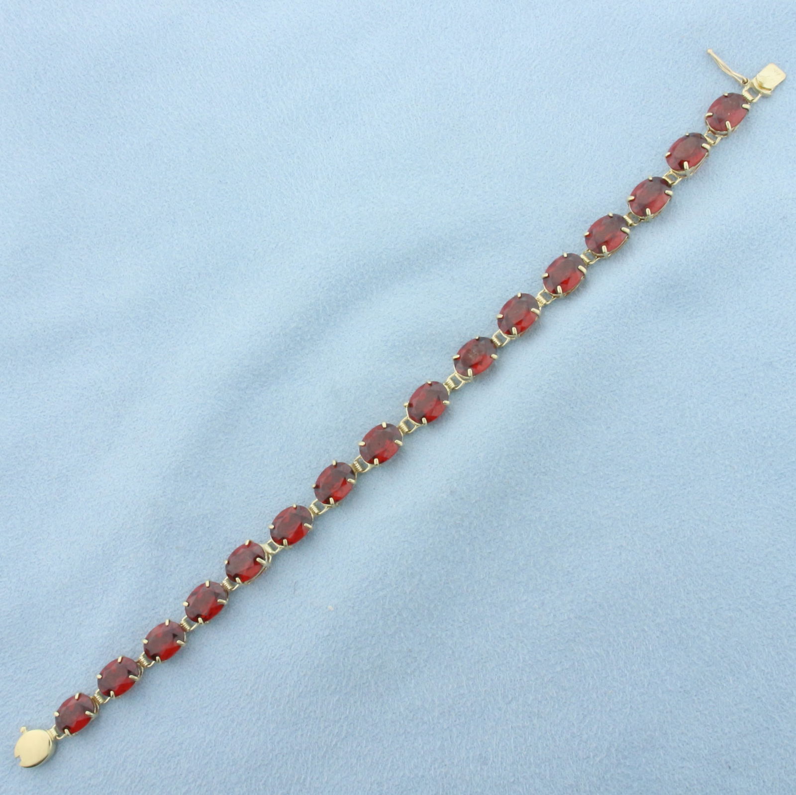 Garnet Tennis Bracelet in 14k Yellow Gold: In 14k Yellow Gold. Contains sixteen 8x6mm high quality natural Garnet gemstones, approximately 22ct TW, with intense color and excellent clarity. 7 inches long. Slide clasp with safety latch. 9.3g.