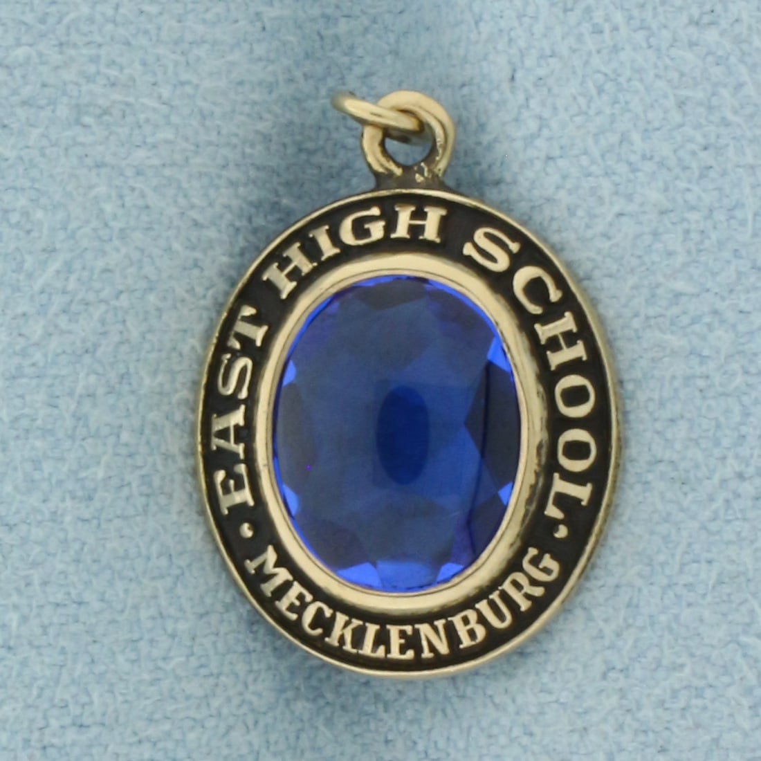 Vintage Mecklenburg East High School Charm or Pendant in 10k Yellow Gold: In 10k Yellow Gold. 3/4 inch long, 1/2 inch wide. Contains one 10mm Lab Sapphire gemstone with intense color and excellent clarity. 2.8g.