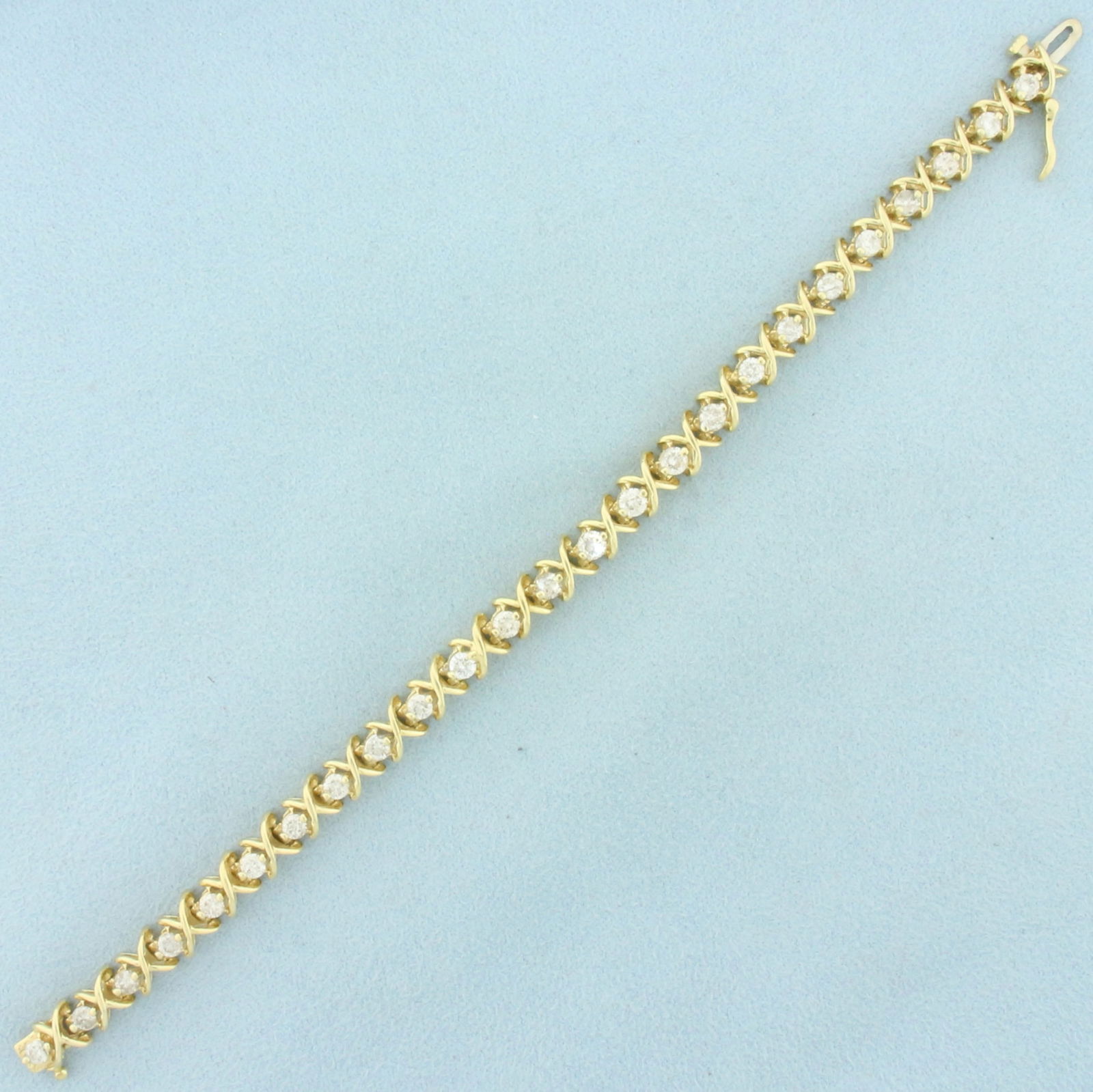 Designer X and O Diamond Tennis Bracelet in 14k Yellow Gold: In 14k Yellow Gold. Contains twenty-five high quality 1/10ct diamonds, H color/I clarity. 7 inches long. 1/4 inch wide. Concealed slide clasp with safety latch. 16.4g.