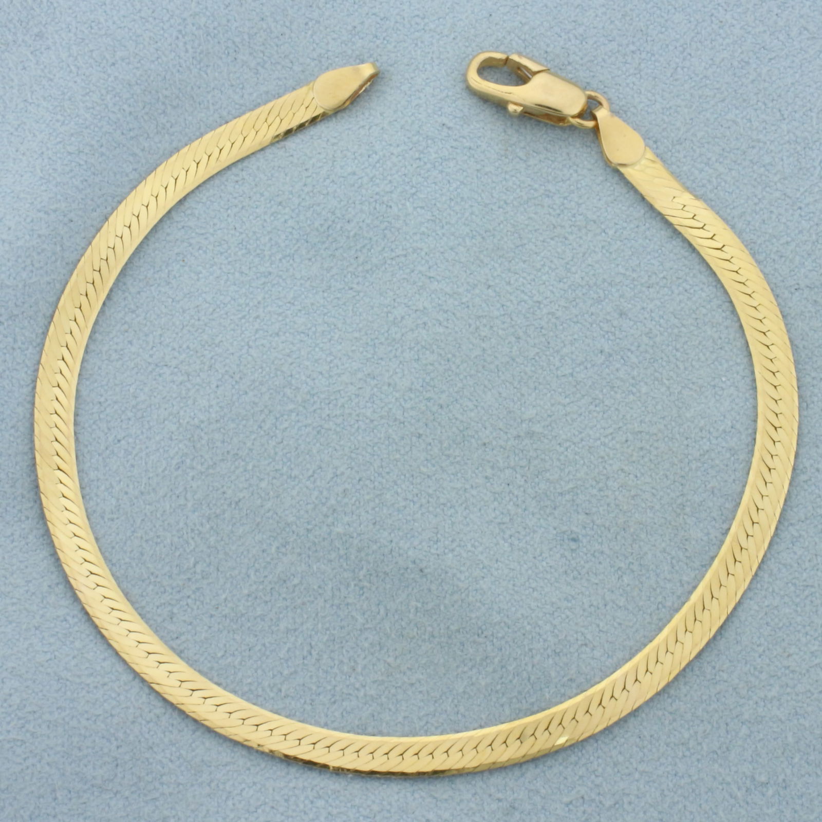 Reversible Herringbone Bracelet in 14k Yellow Gold: In 14k Yellow Gold. 7 1/8 inches long. 3.3mm wide. Lobster clasp. Different patterns on either side. 3.6g.