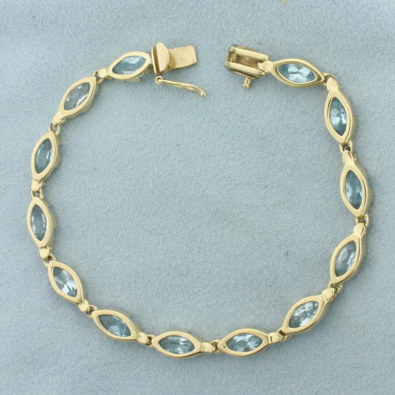 Sky Blue Topaz Tennis Bracelet in 14k Yellow Gold: In 14k Yellow Gold. Contains thirteen 7x3.5mm high quality Sky Blue Topaz gemstones with bright color and excellent clarity. 7 inches long. 5.3mm wide. Slide clasp with safety latch. 10.2g.