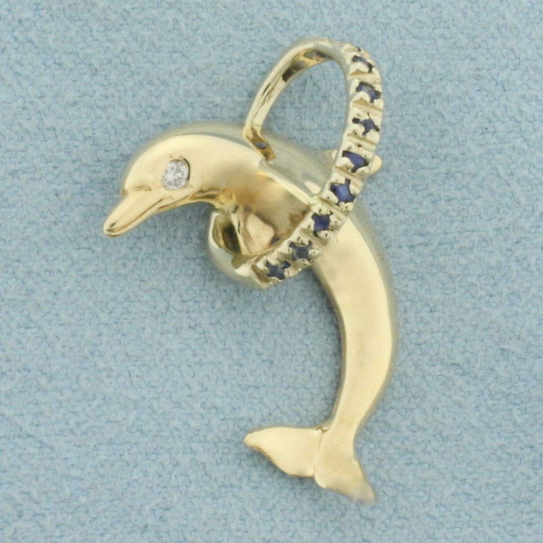 Sapphire and Diamond Dolphin Pendant in 14k Yellow Gold: In 14k Yellow Gold. Contains one .01ct high quality diamond. Also contains ten 1.5mm high quality natural Sapphire gemstones with intense color and excellent clarity. 1 inch long. 3/4 inch wide. 3.0g