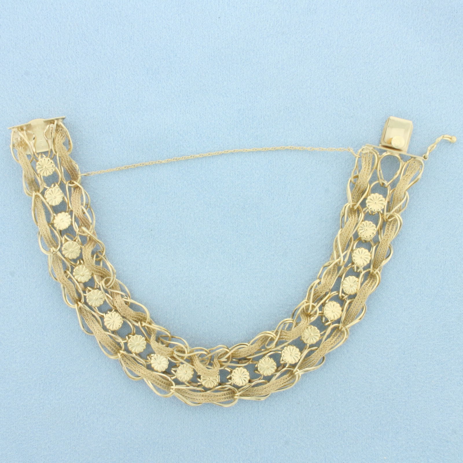 Woven Flower Design Bracelet in 14k Yellow Gold: In 14k Yellow Gold. 7 3/4 inches long. 5/8 inch wide. Concealed slide clasp with safety latch and chain. 19.5g.