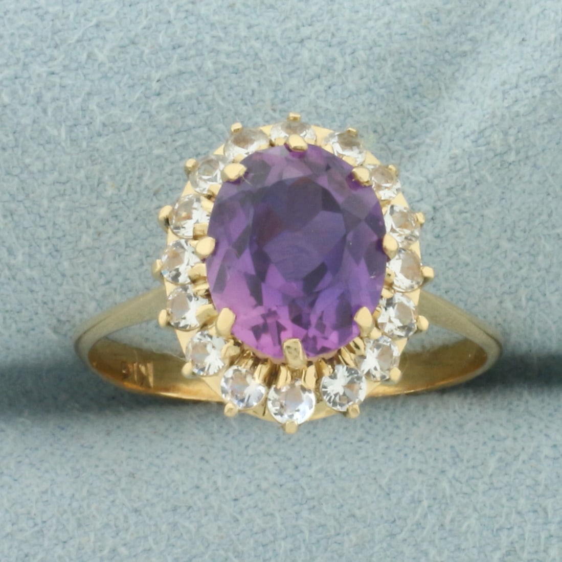 Lavendar and White Sapphire Halo Ring in 18k Yellow Gold: In 18k Yellow Gold. Contains one 10x8mm high quality natural Lavendar Sapphire gemstone, approximately 3cts, with vibrant color and excellent clarity. Also contains sixteen .03ct high quality white sa
