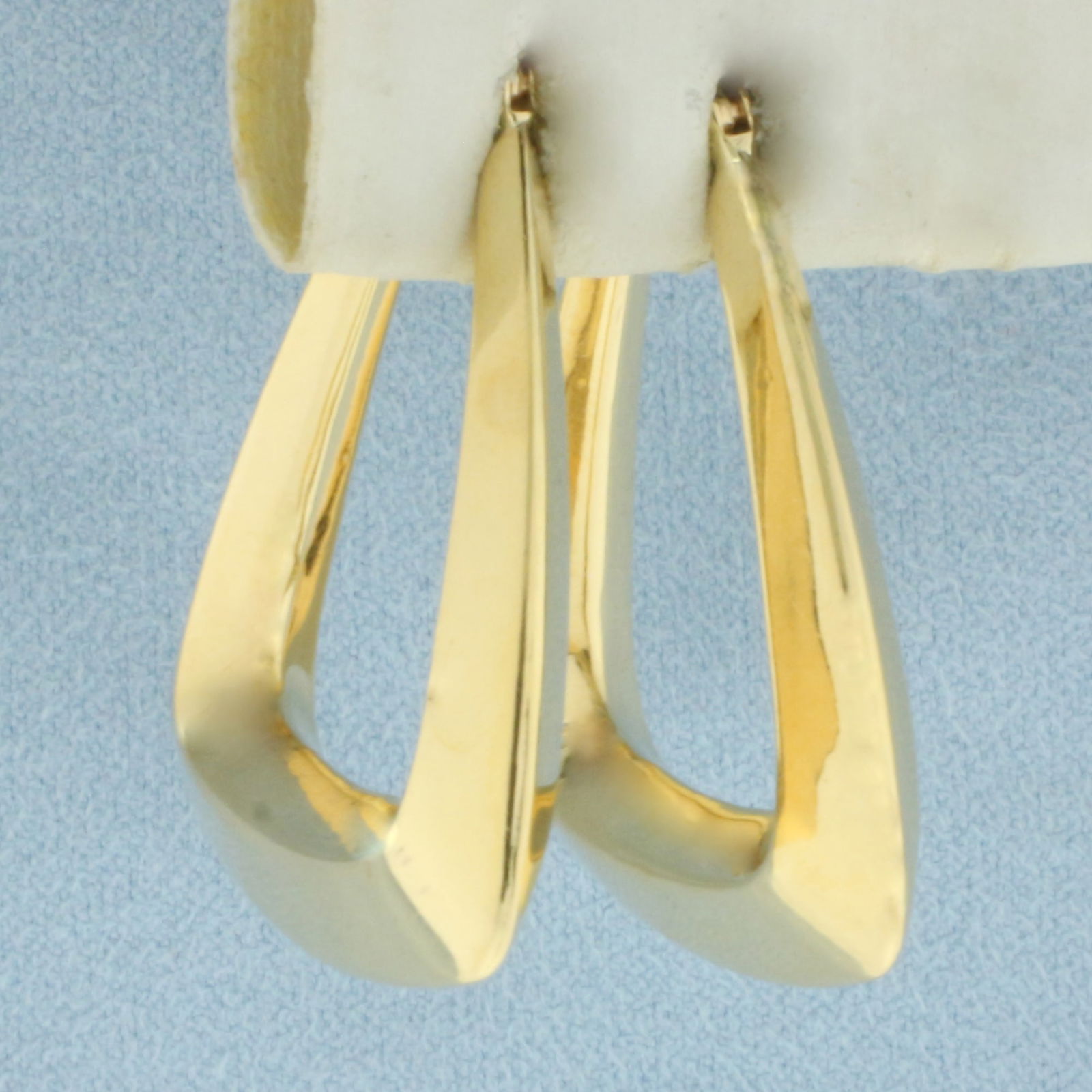 Puffy Triangle Hoop Earrings in 14k Yellow Gold: In 14k Yellow Gold. 1 1/4 inch long. 1 1/8 inch wide. Leverback. 5.0g.