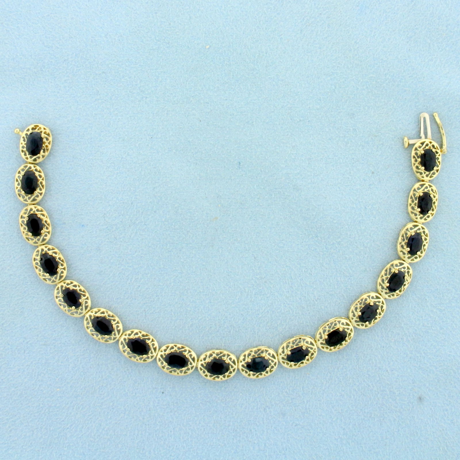 Vintage Filigree Natural Sapphire Line Tennis Bracelet in 10K Yellow Gold: In 10K Yellow Gold. Contains seventeen high quality natural 6x4mm oval cut Sapphire gemstones with deep blue color. 7 inches long. 3/8 inch wide. 9.5g