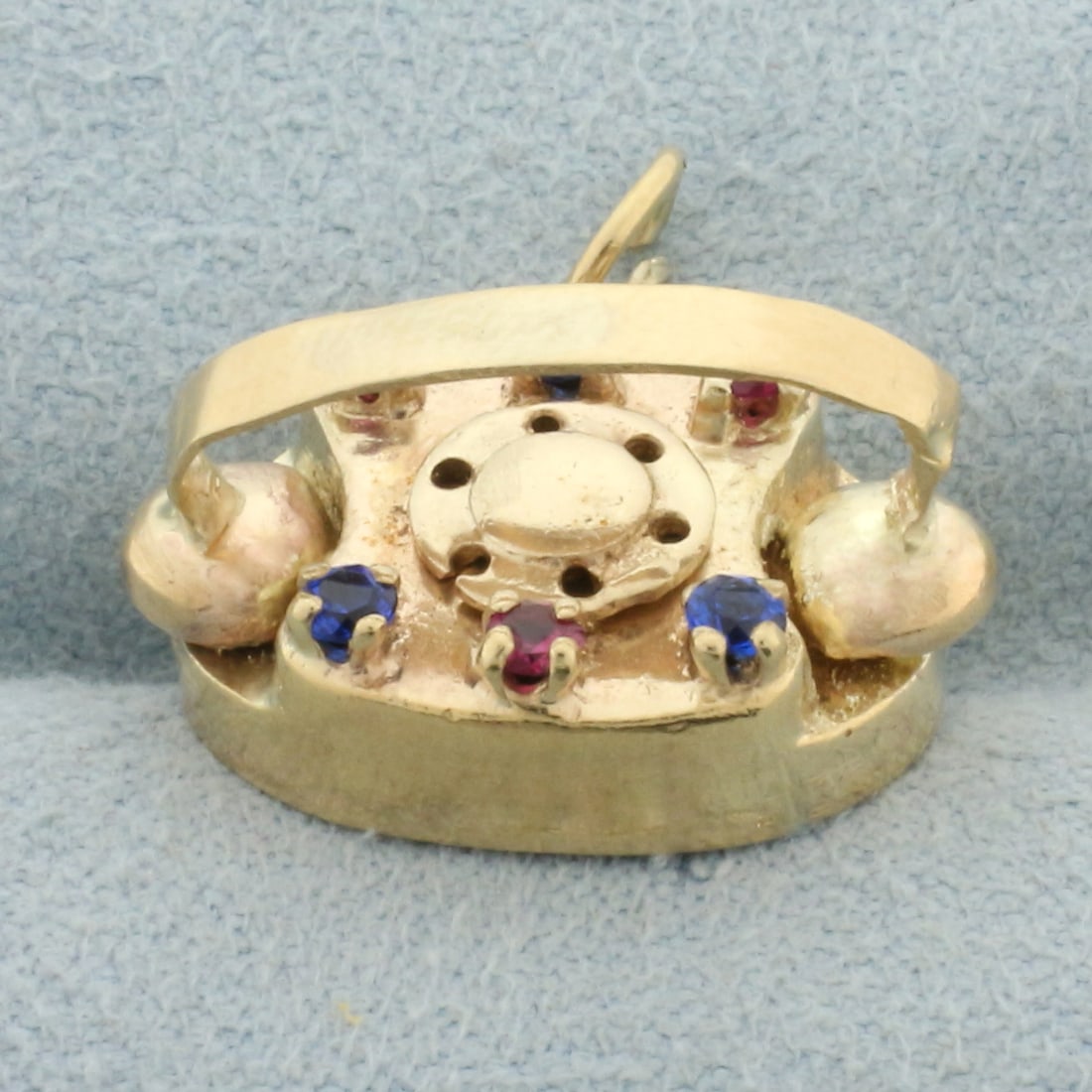 Sapire and Ruby Rotary Telephone Charm in 14k Yellow Gold: In 14k yellow gold. Contains three Ruby and three Sapphire high quality 2mm gemstones with vibrant color. 5/8 inches long (not including jump ring) by 3/4 inches wide. 5.2g.