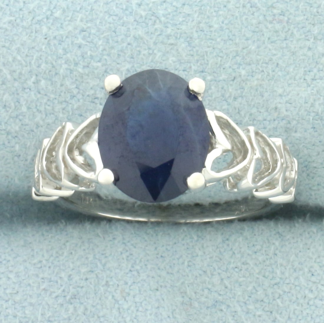 Sapphire Heart Design Ring in 14k White Gold: In 14k white gold. Contains one high quality natural 10mm by 8mm oval sapphire gemstone, approximately 2.5cts, with intense color and e excellent clarity. Heart design on shoulders of ring. Size: 6. 4