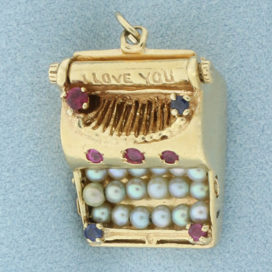 I Love You Gemstone Typewriter Charm or Pendant in 14k Yellow Gold: In 14k yellow gold. Contains five high quality 2mm natural Ruby gemstones. Also contains two high quality natural 2mm Sapphire gemstones. Lastly contains eighteen high quality seed pearls. 1 1/8 inche