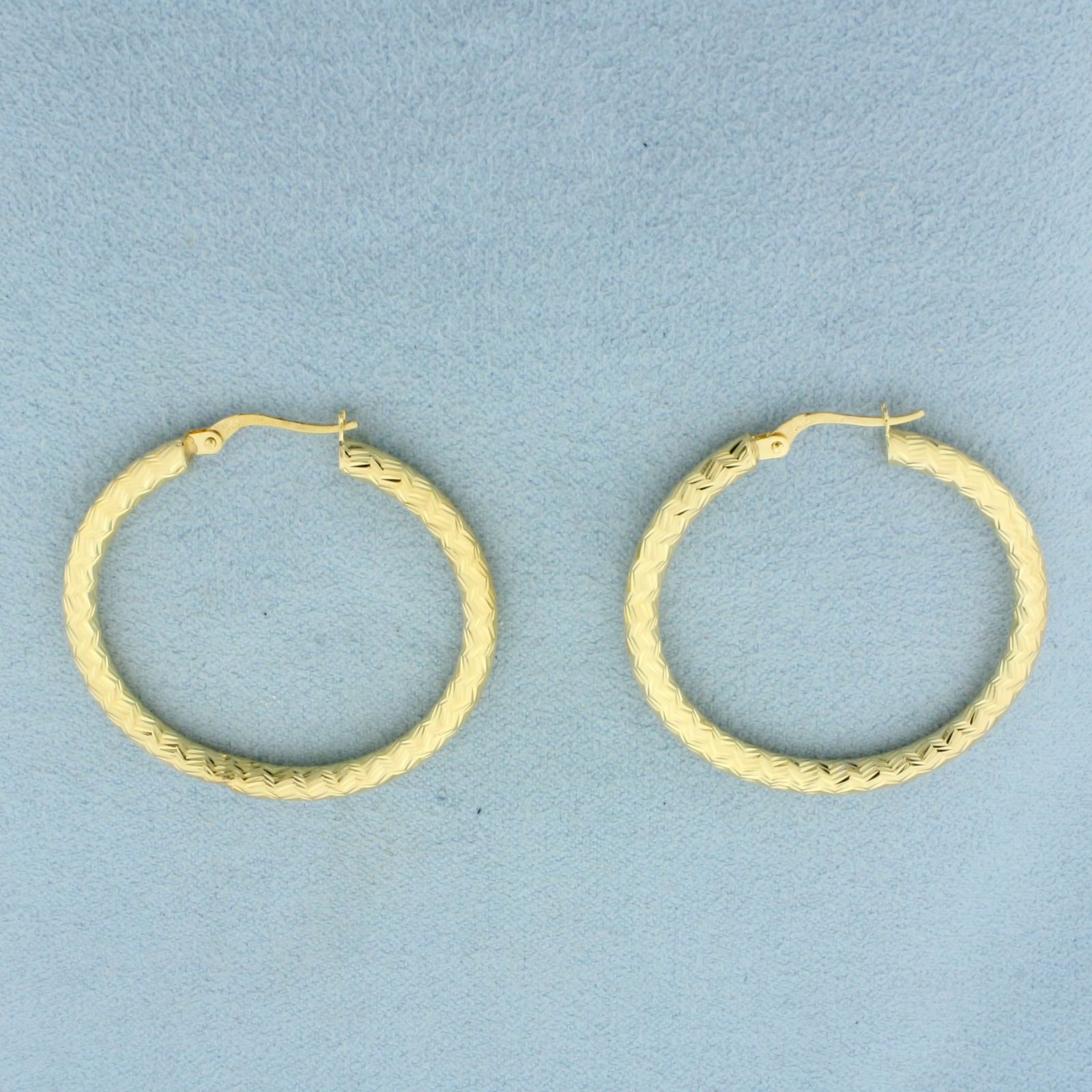 Diamond Cut Zigzag Design Hoop Earrings in 14k Yellow Gold: In 14k Yellow Gold. 1 3/8 inches long. 1 3/8 inches wide. Small indent on bottom of one, not noticeable. 2.4g.