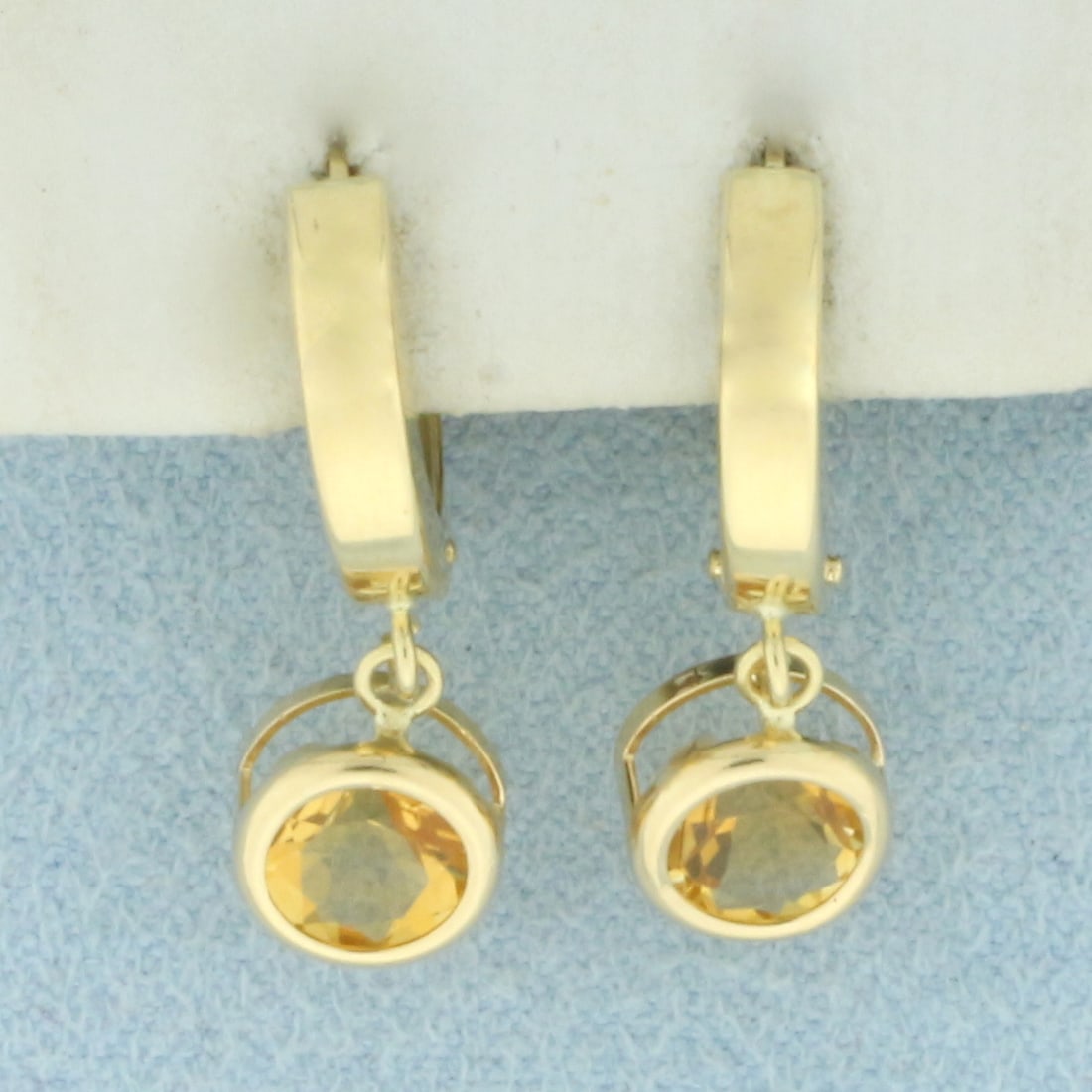 Citrine Bezel Set Dangle Hoop Earrings in 14k Yellow Gold: In 14k Yellow Gold. Contains two 6mm high quality natural Citrine gemstones with intense golden color and excellent clarity. 7/8 inch long. 1/2 inch wide. Locking leverbacks. 1.7g.